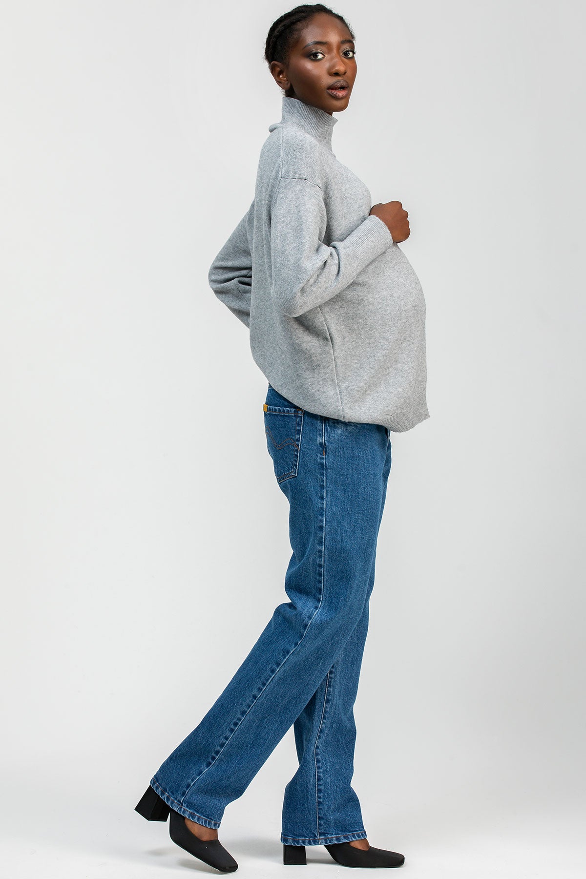 Modella indossa jeans premaman dritti a vita alta con fascia elastica comoda, abbigliamento premaman elegante.