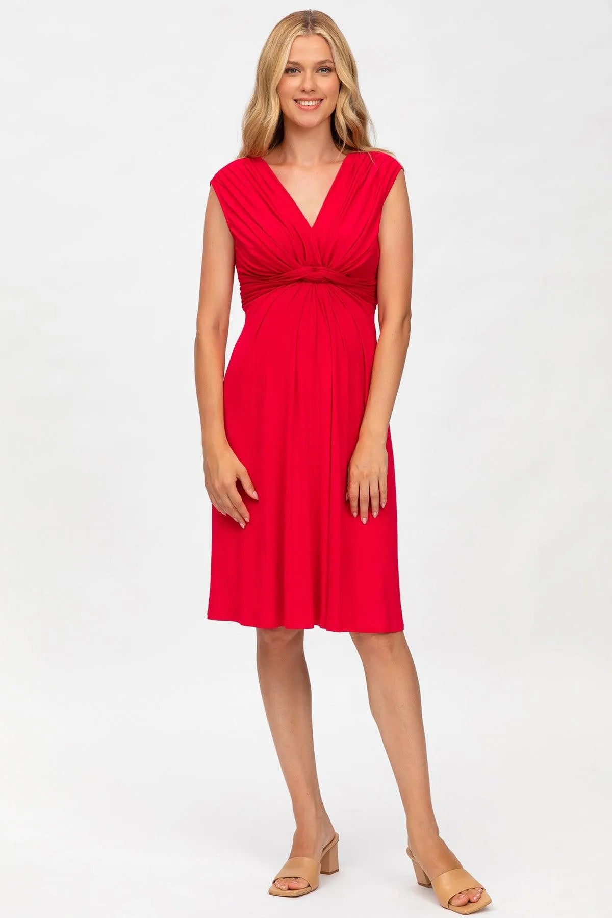 Donna incinta indossa abito premaman rosso elegante a vita alta, sfondo bianco.