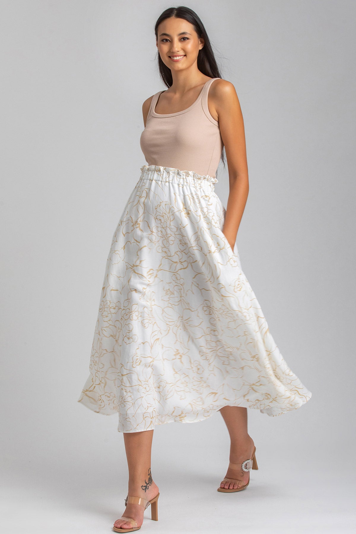 Donna incinta indossa una gonna lunga premaman bianca con motivo floreale beige e top beige