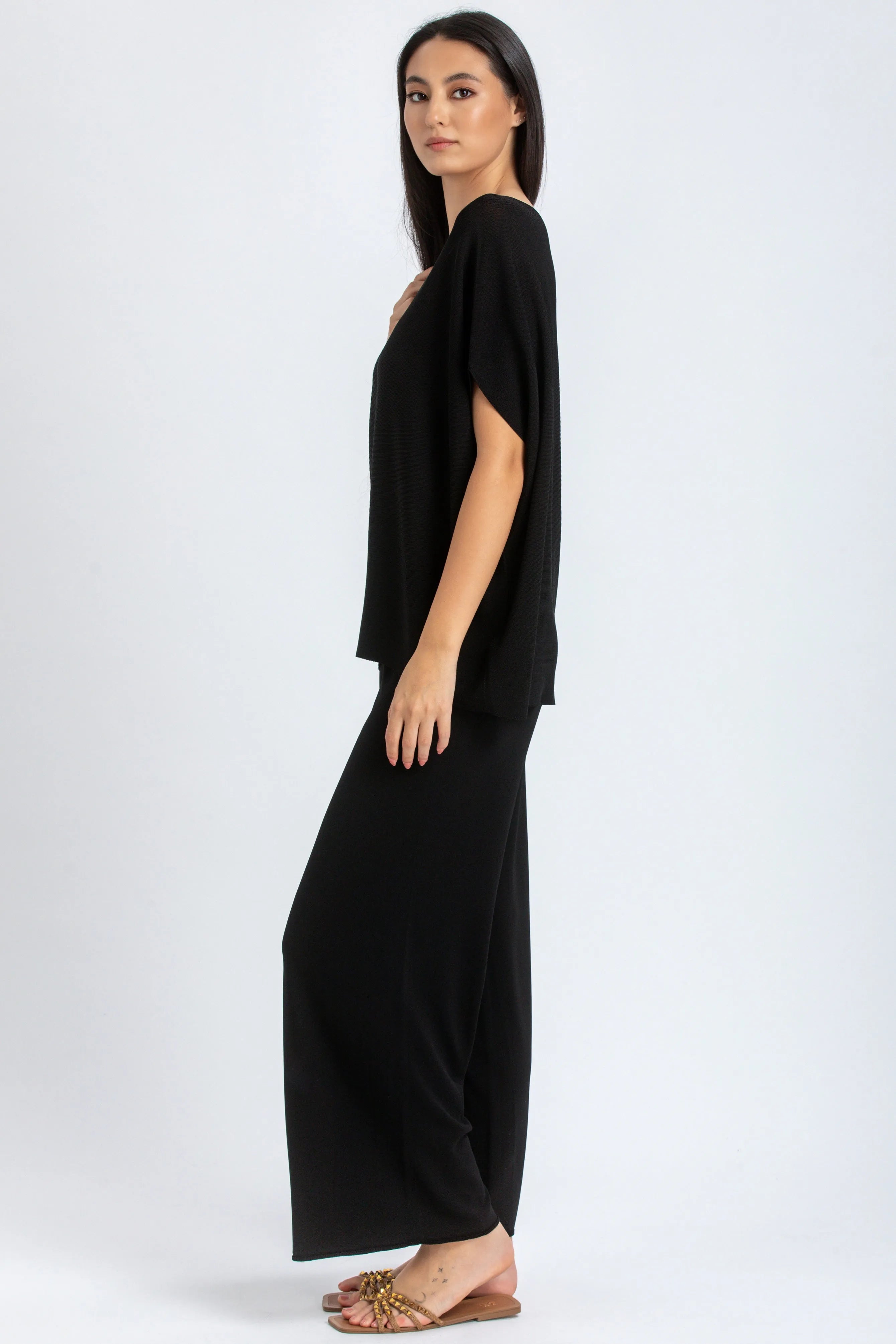 Donna indossa un completo premaman nero elegante con maglia ampia e pantaloni larghi.