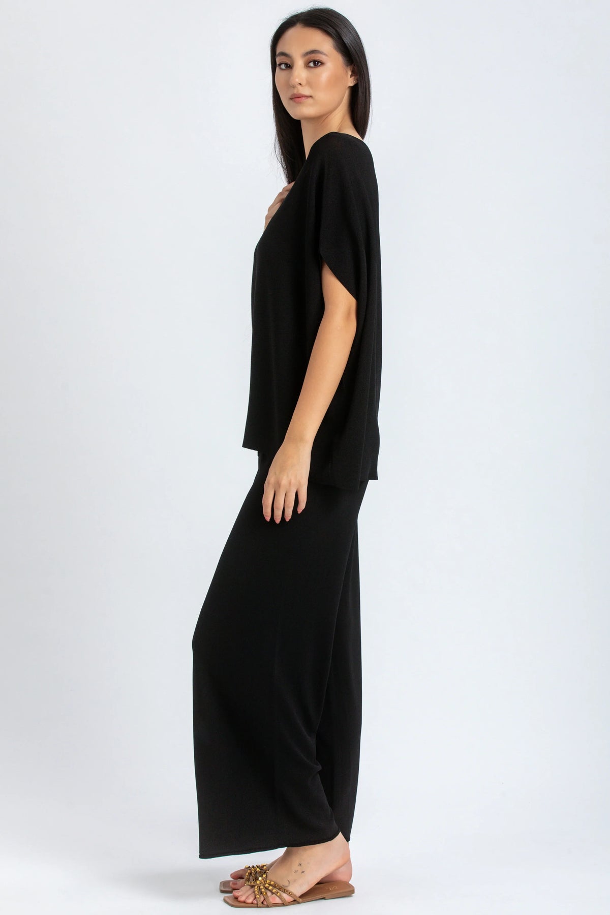 Donna indossa un completo premaman nero elegante con maglia ampia e pantaloni larghi.