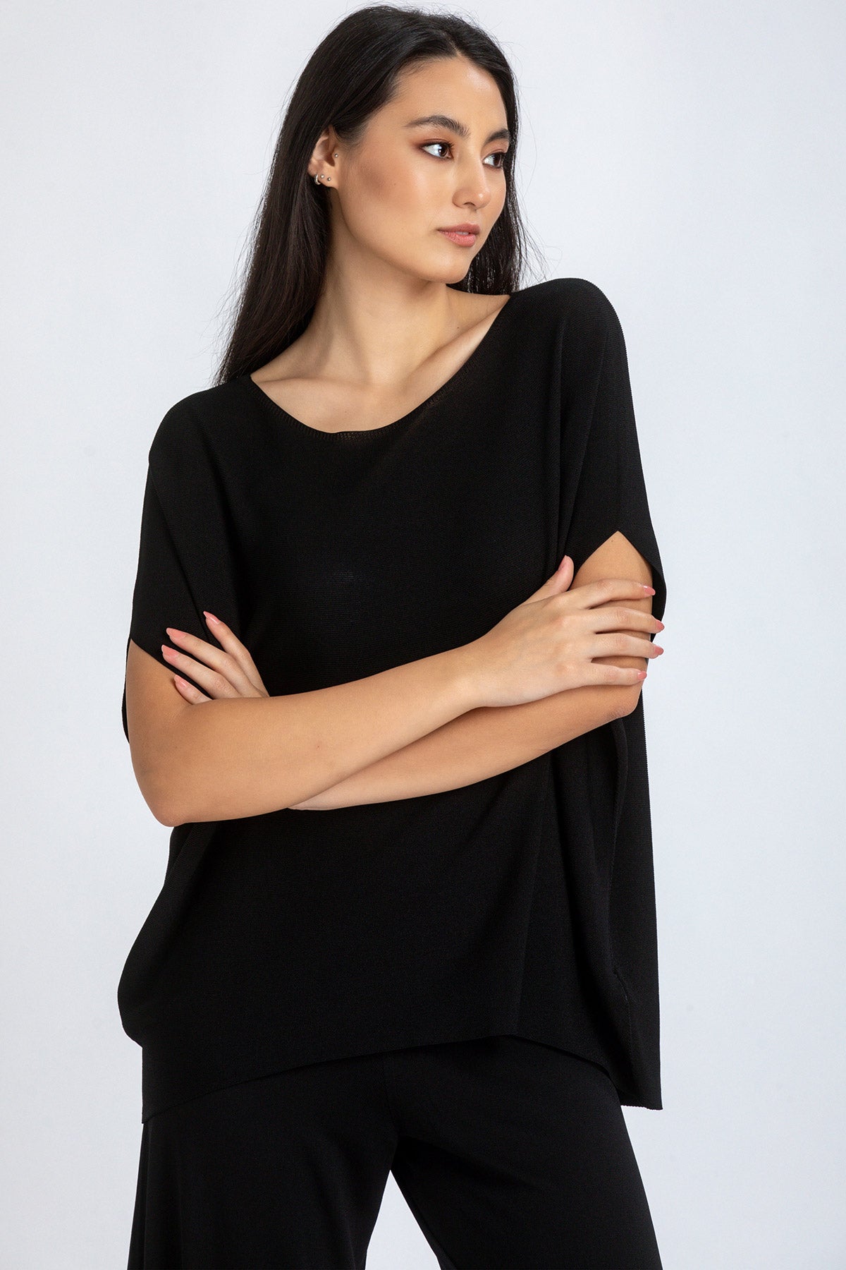 Modella indossa maglia premaman nera a maniche corte dal taglio morbido, sfondo chiaro.
