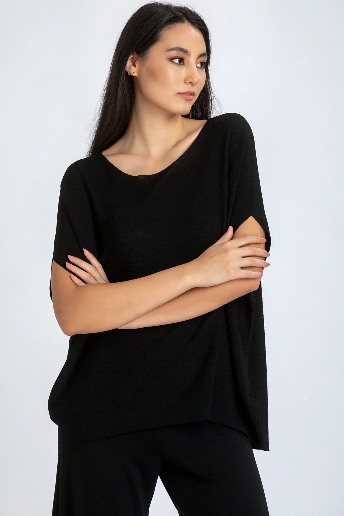 Modella indossa maglia premaman nera a maniche corte dal taglio morbido, sfondo chiaro.