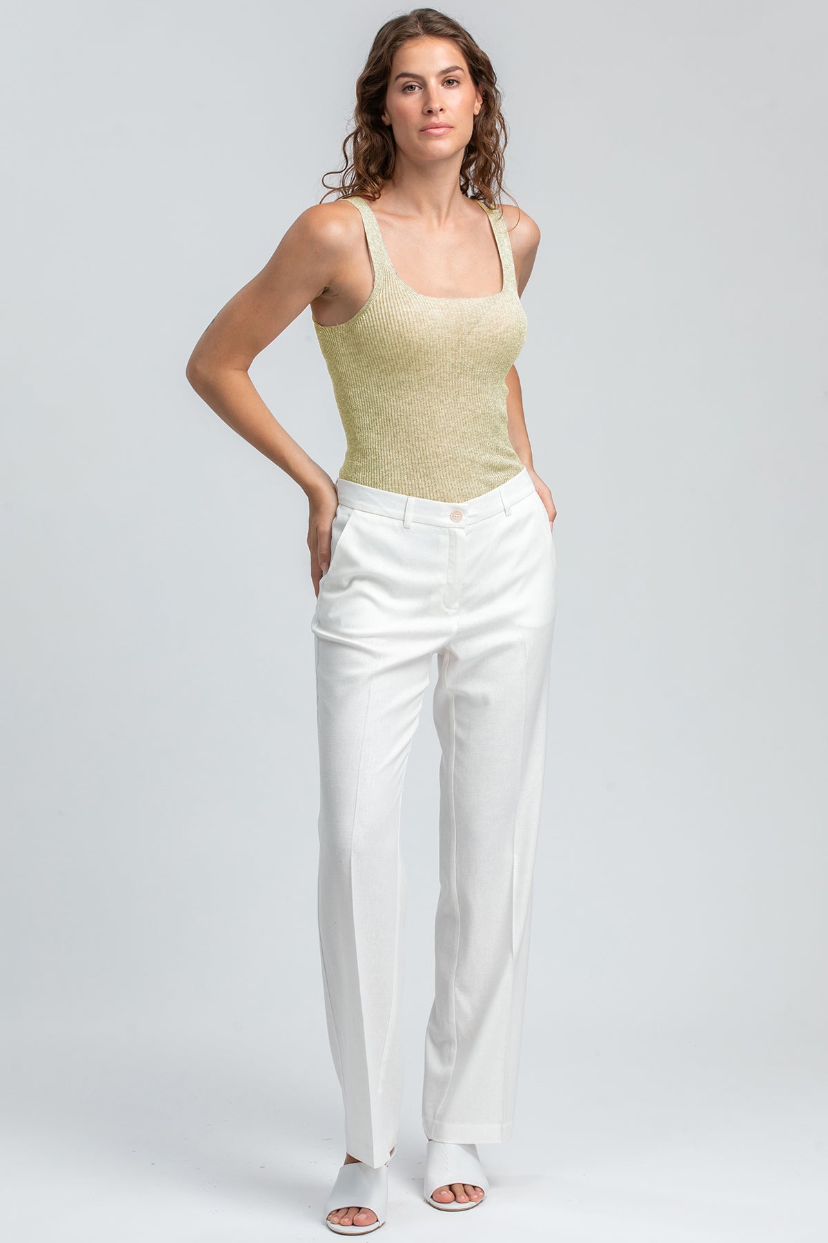 Modella con pantaloni premaman bianchi eleganti e top senza maniche, abbigliamento premaman.