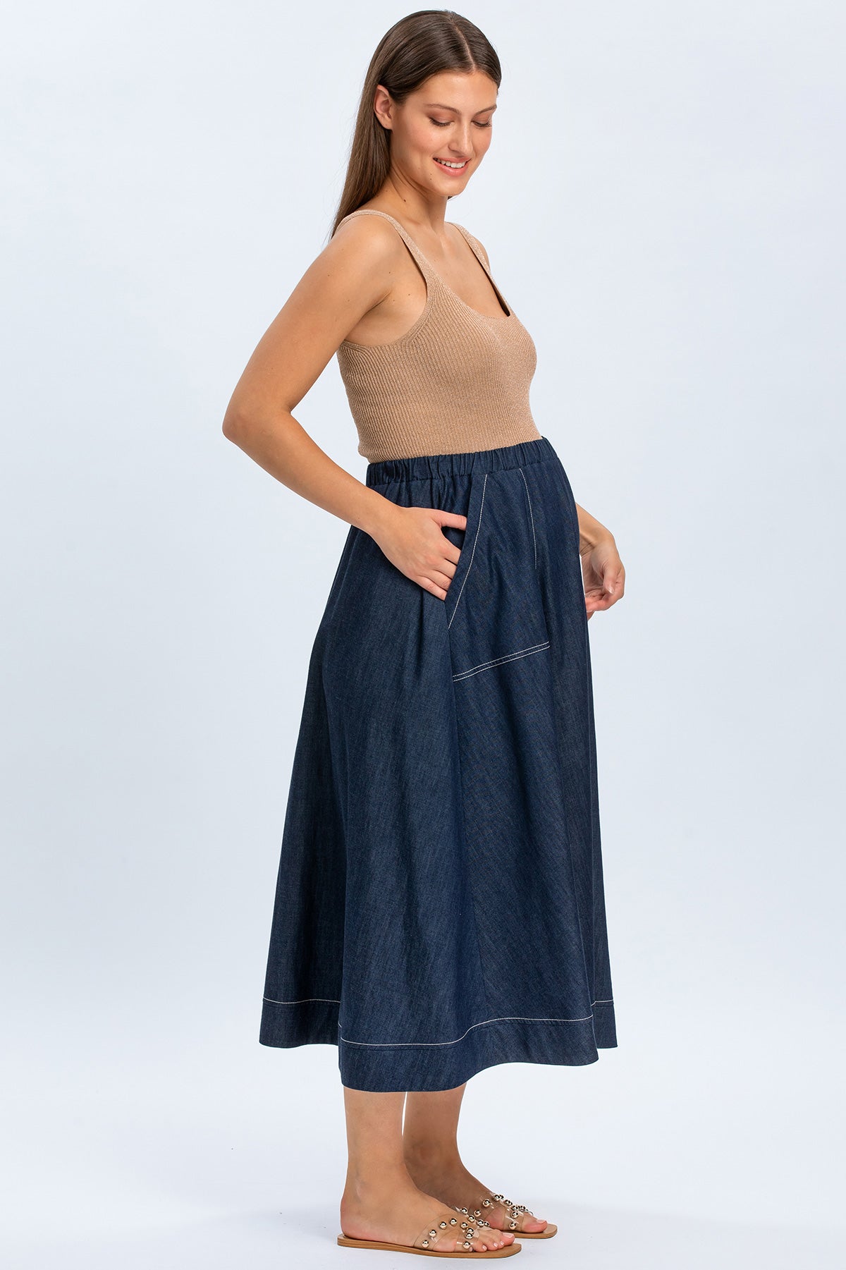 Modella indossa una gonna premaman in denim blu con elastico in vita e top beige.