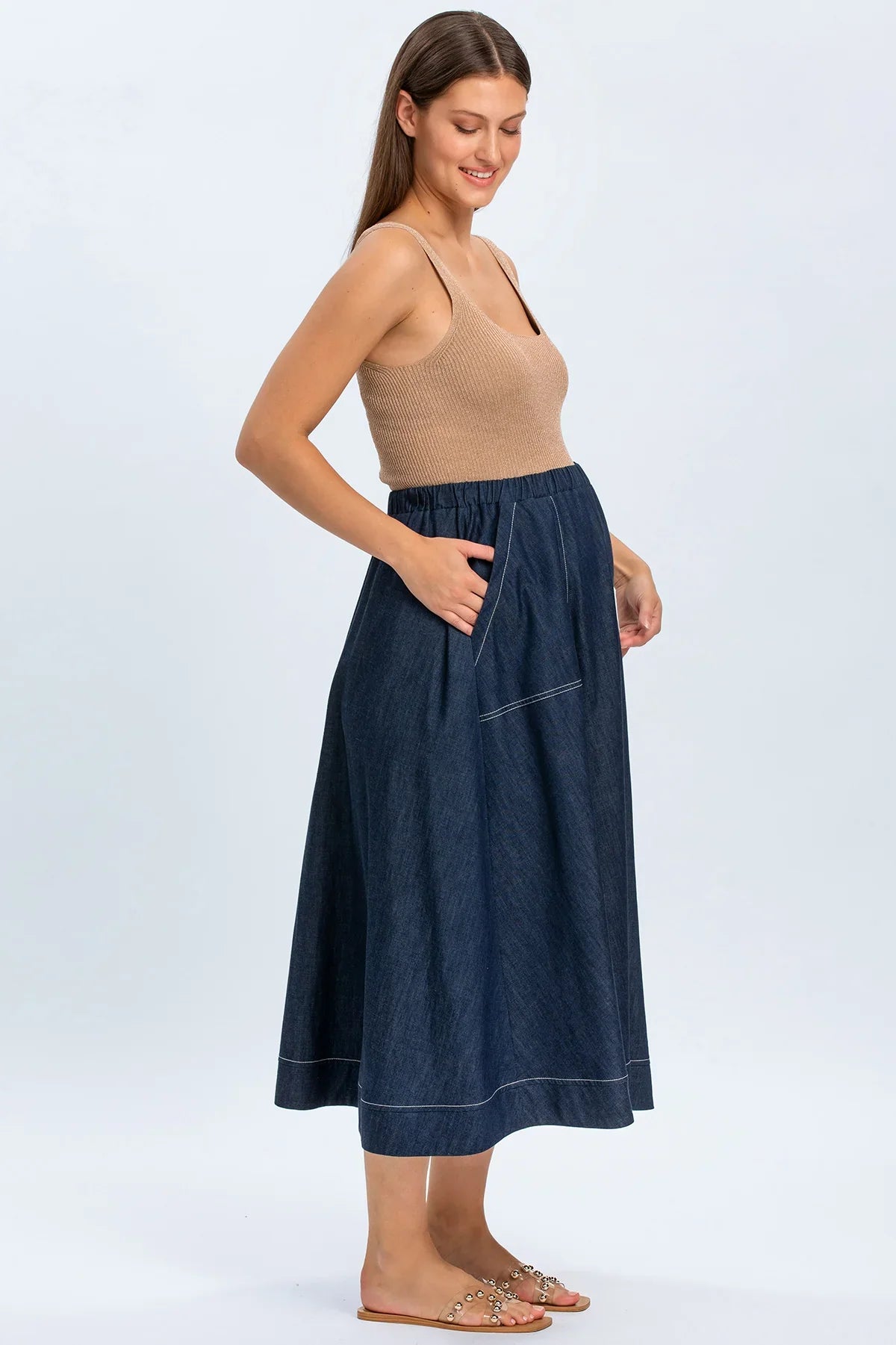 Modella indossa una gonna premaman in denim blu con elastico in vita e top beige.