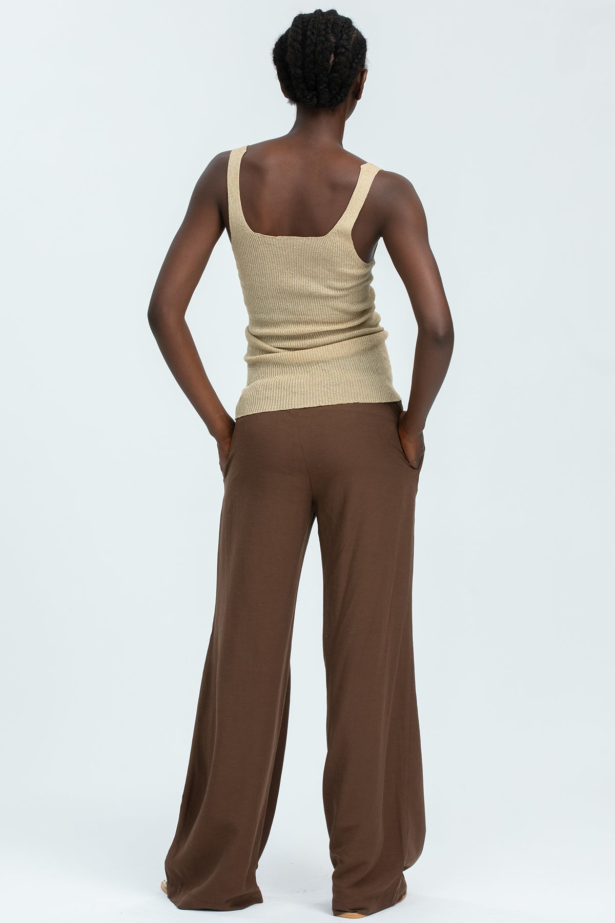 Abbigliamento premaman: donna con top beige e pantaloni larghi marroni vista retro