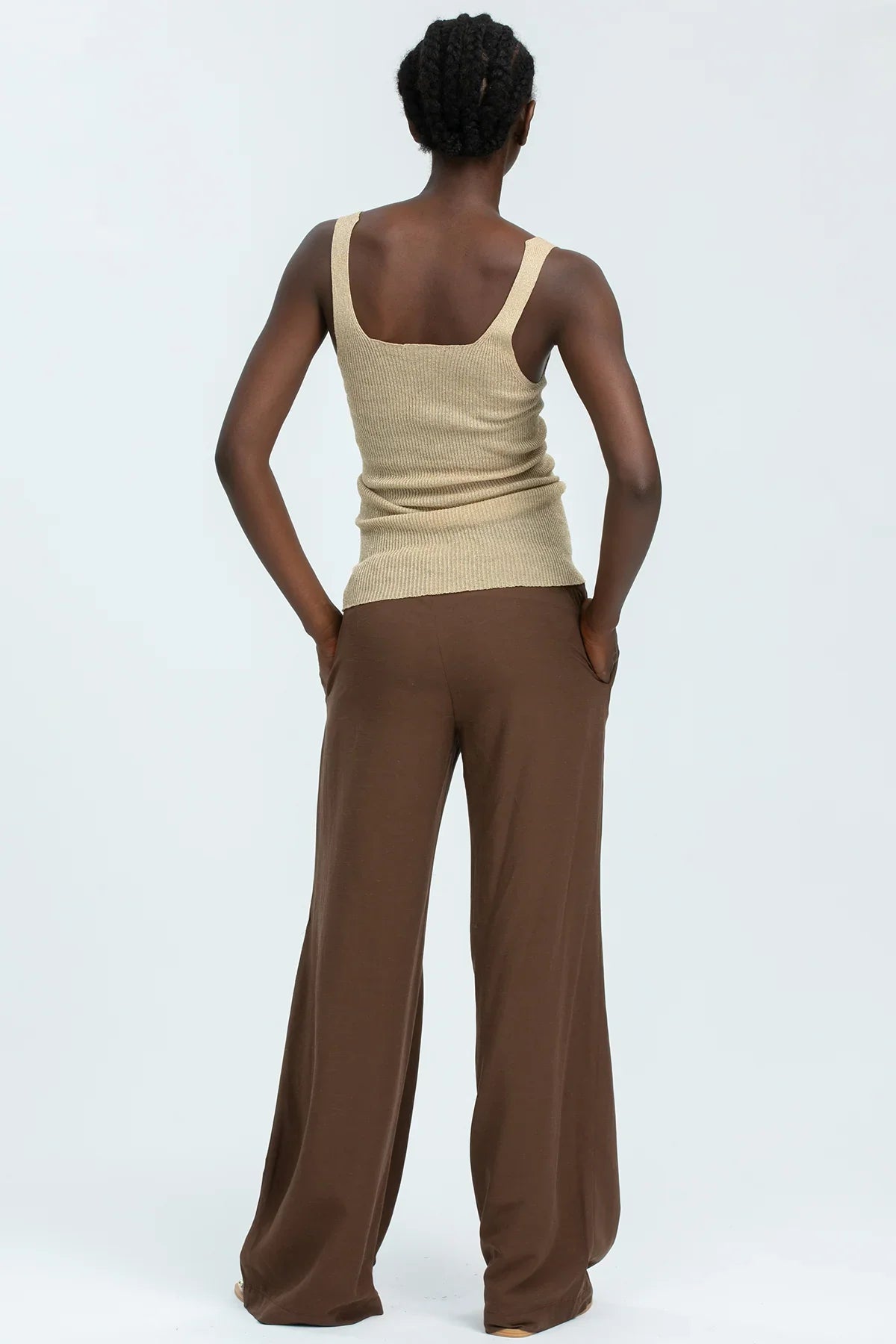 Abbigliamento premaman: donna con top beige e pantaloni larghi marroni vista retro