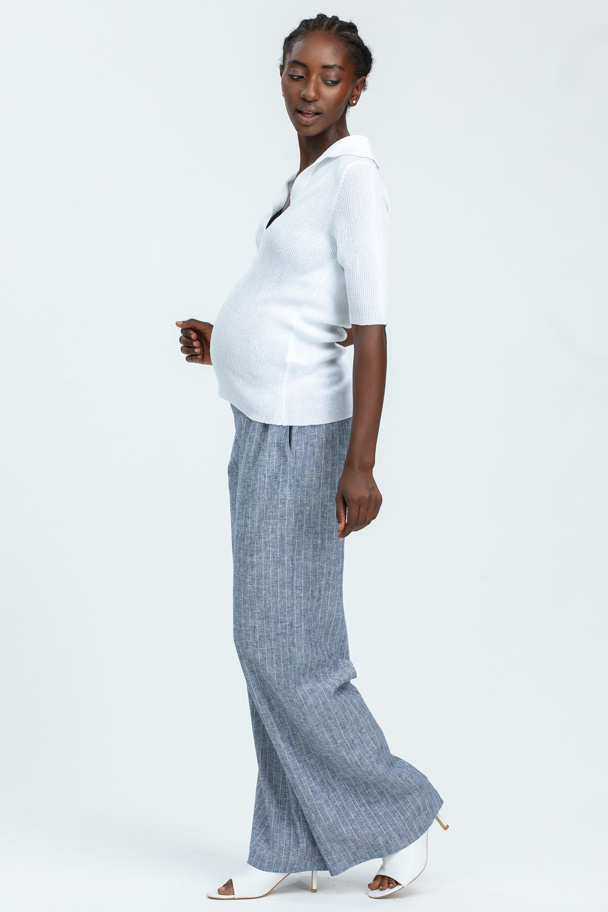 Modella incinta con maglia premaman bianca e pantaloni larghi grigi, outfit premaman elegante
