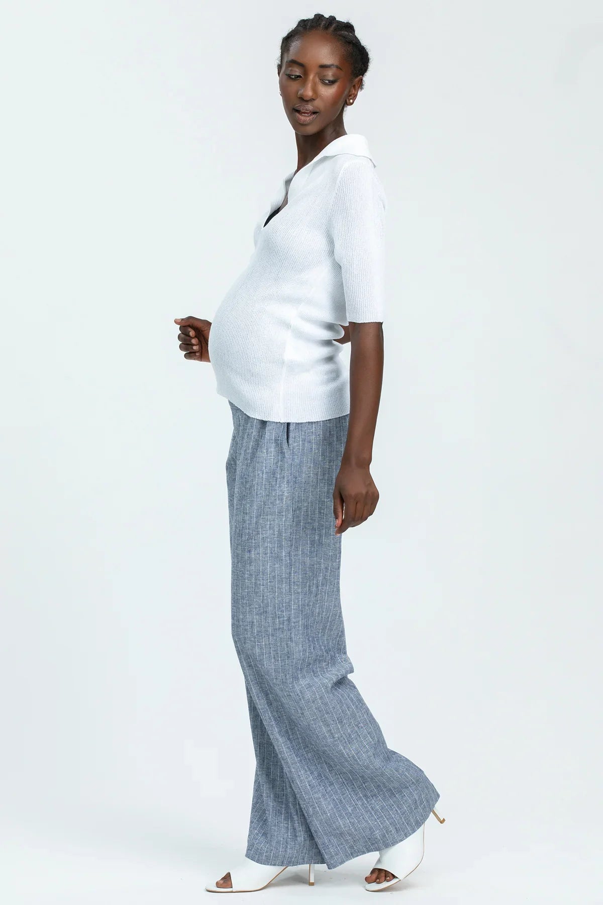 Modella incinta con maglia premaman bianca e pantaloni larghi grigi, outfit premaman elegante