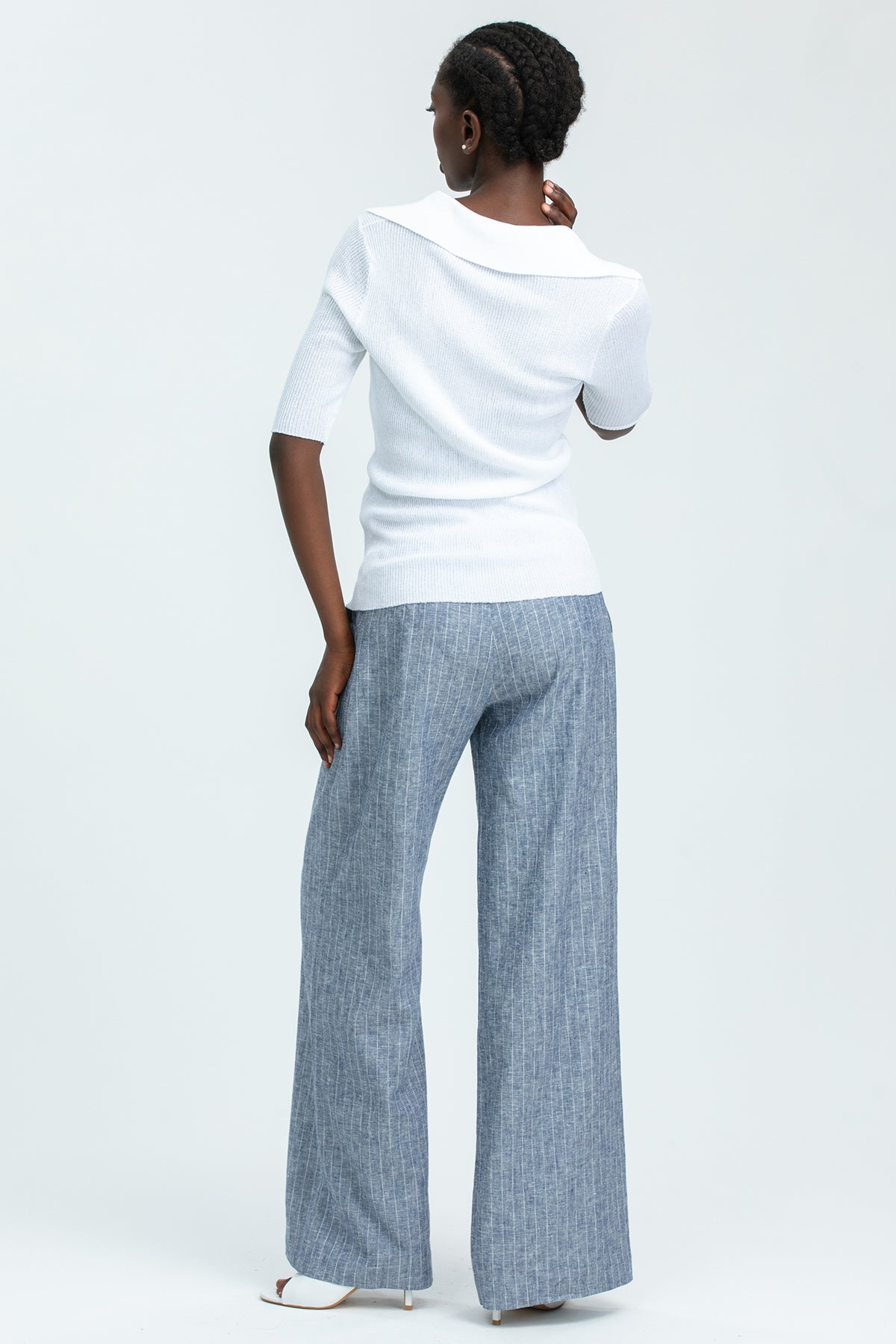 Donna di spalle con pantaloni premaman a righe blu e maglia bianca, abbigliamento premaman elegante