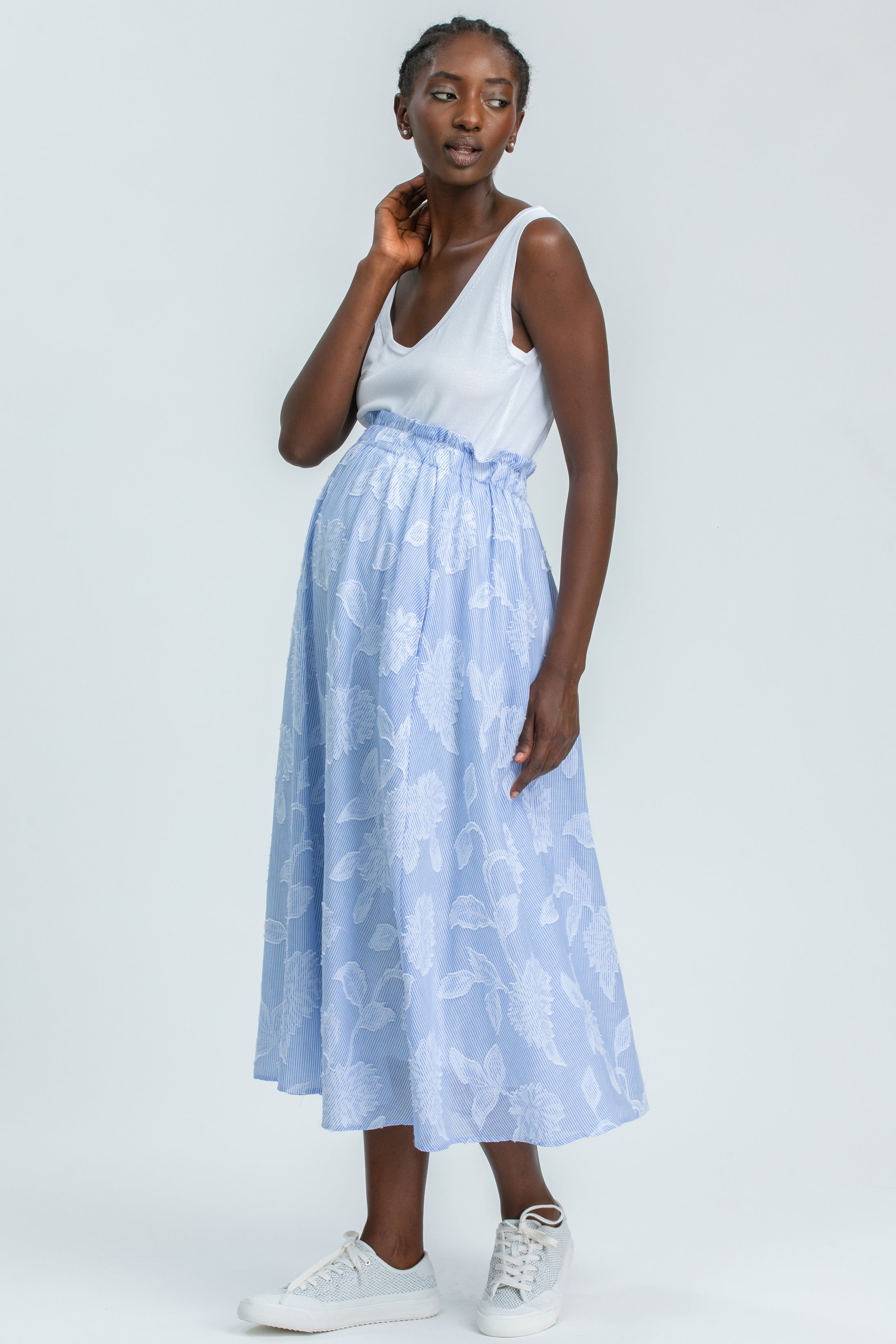 Modella indossa una gonna premaman azzurra lunga con fantasia floreale, look premaman elegante.