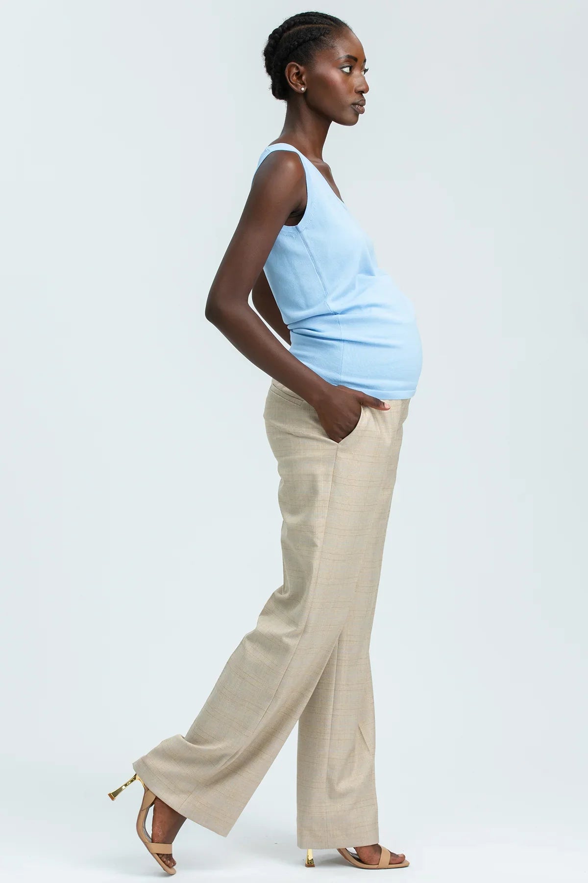 Modella indossa pantaloni premaman beige eleganti e top azzurro, abbigliamento premaman moderno.