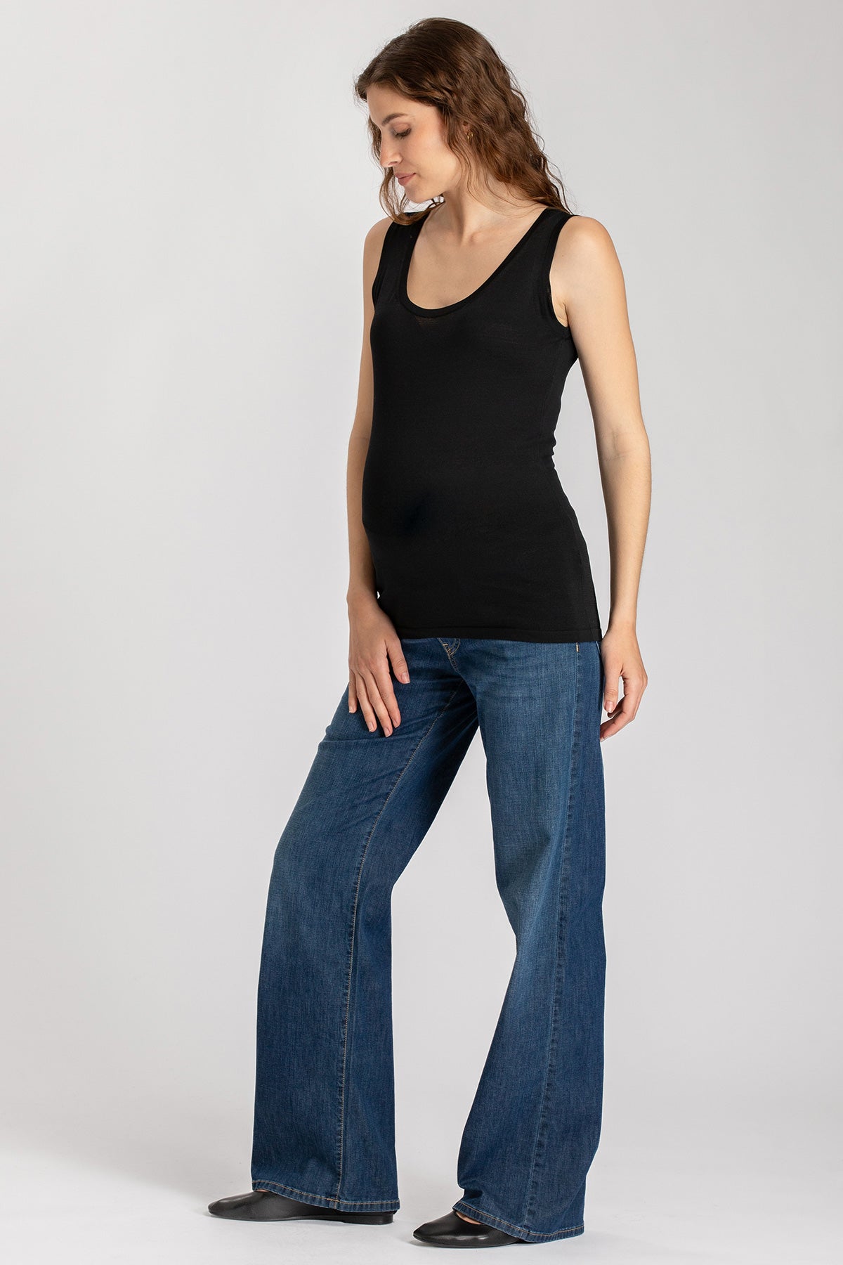 Modella premaman con canotta nera e jeans larghi, abbigliamento premaman elegante.