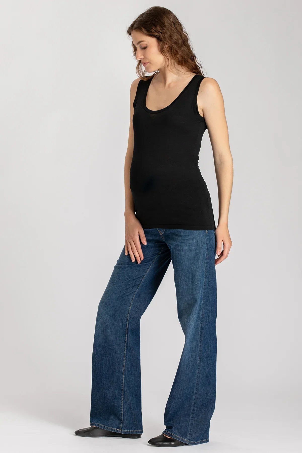 Modella premaman con canotta nera e jeans larghi, abbigliamento premaman elegante.