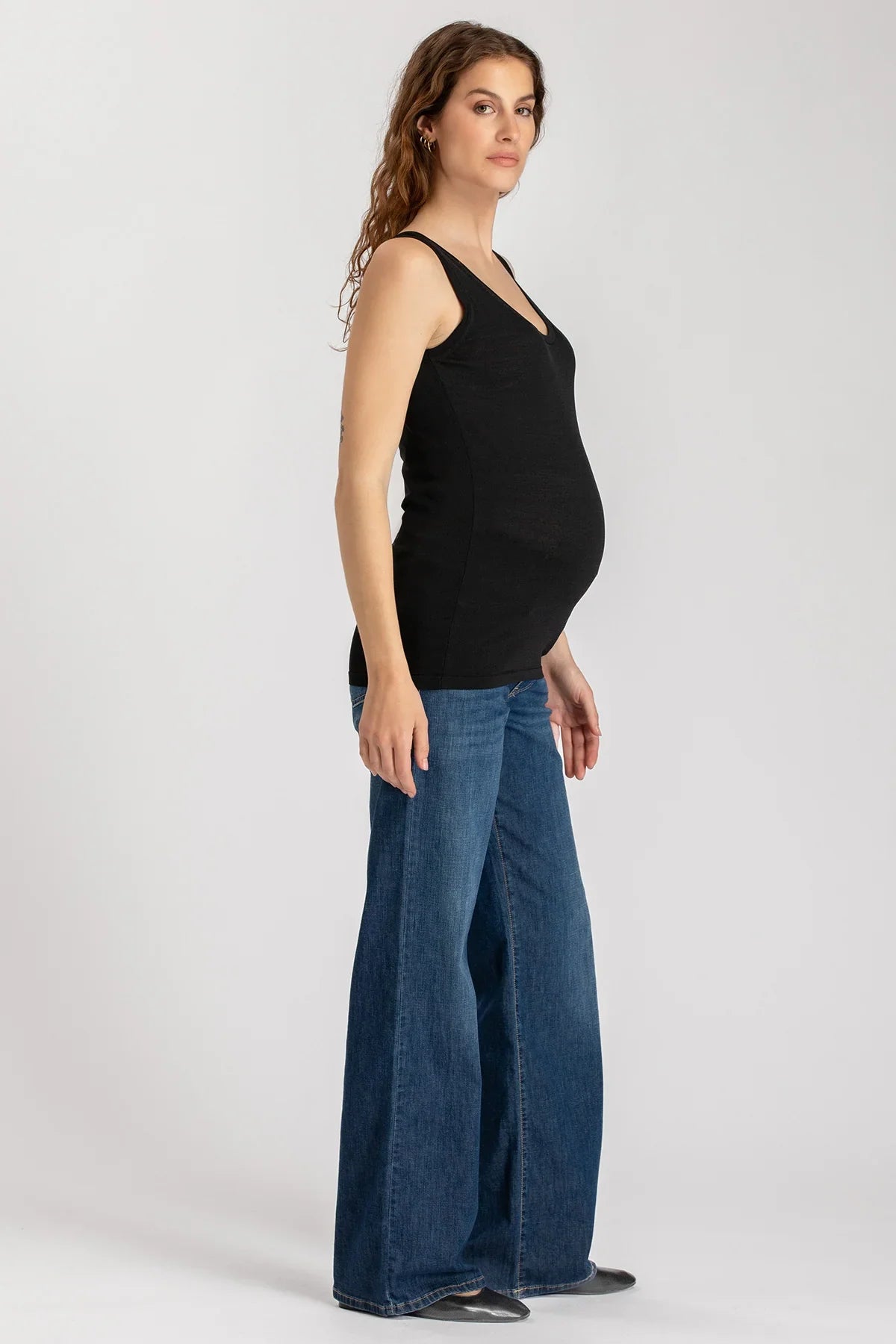 Donna incinta con top nero e jeans premaman a zampa, abbigliamento premaman elegante