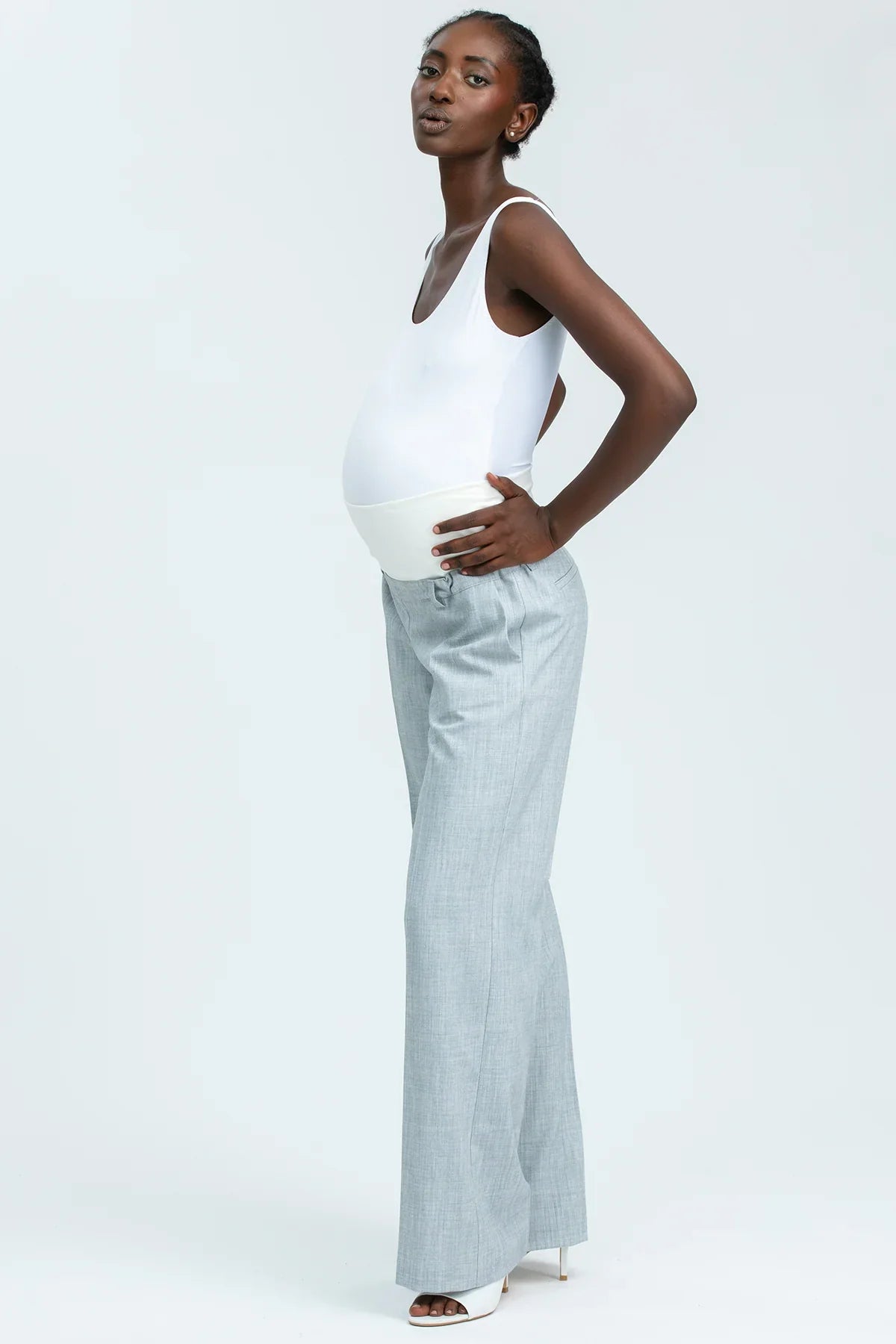 Modella indossa pantaloni premaman eleganti grigi e top bianco, abbigliamento premaman