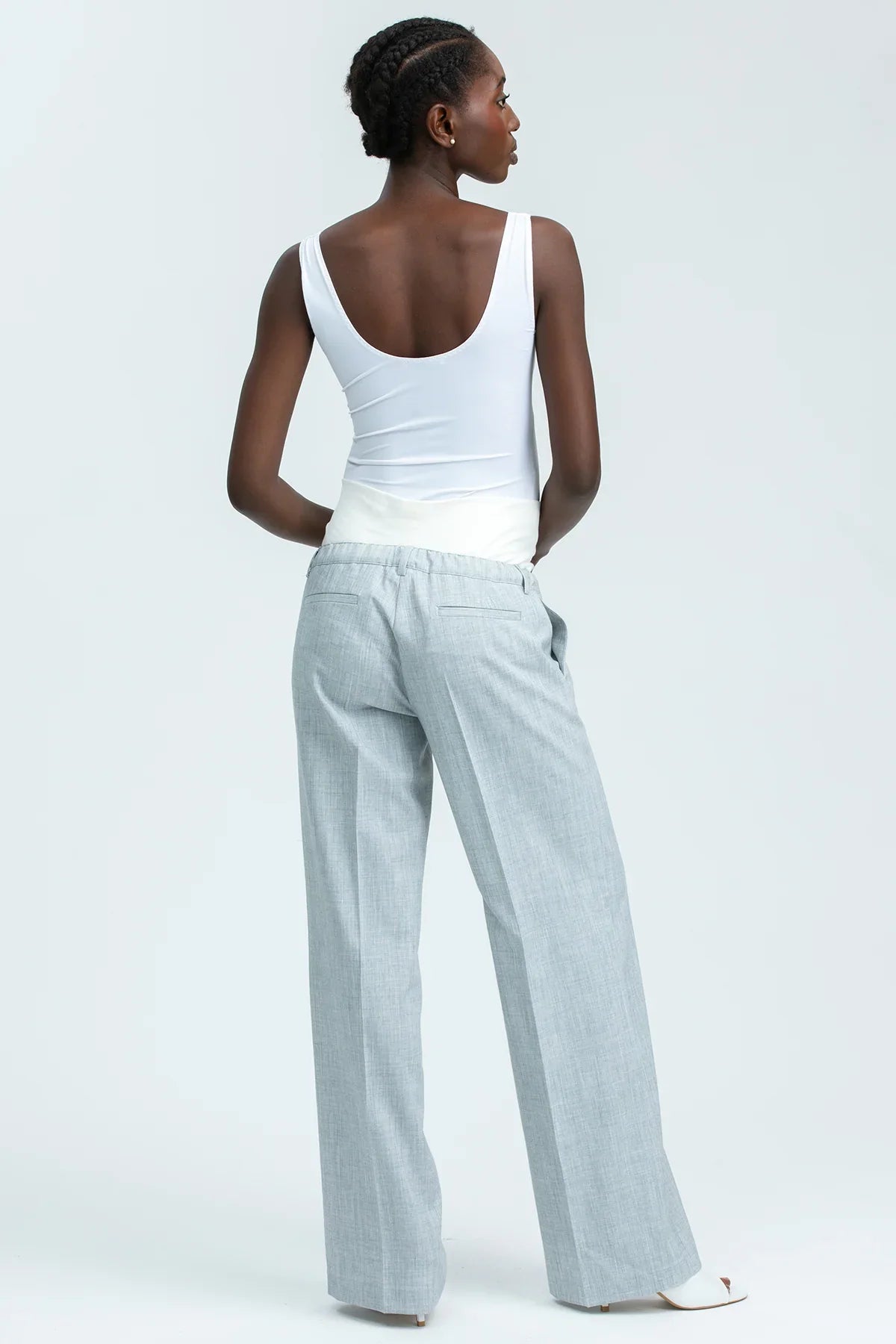 Pantaloni premaman grigi a gamba larga con fascia in jersey bianca, indossati da donna.