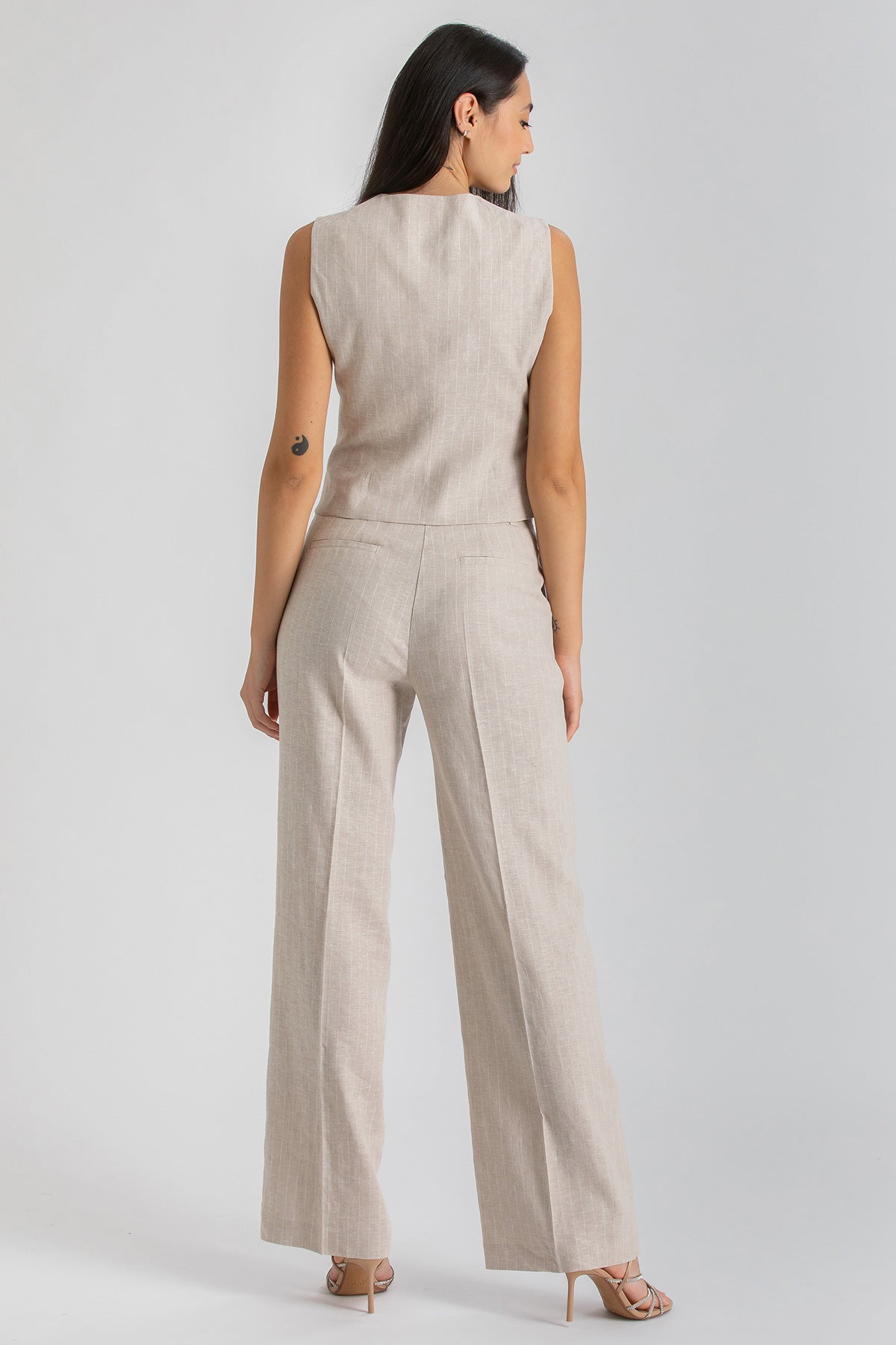 Donna di spalle indossa completo premaman beige senza maniche, abbigliamento premaman elegante