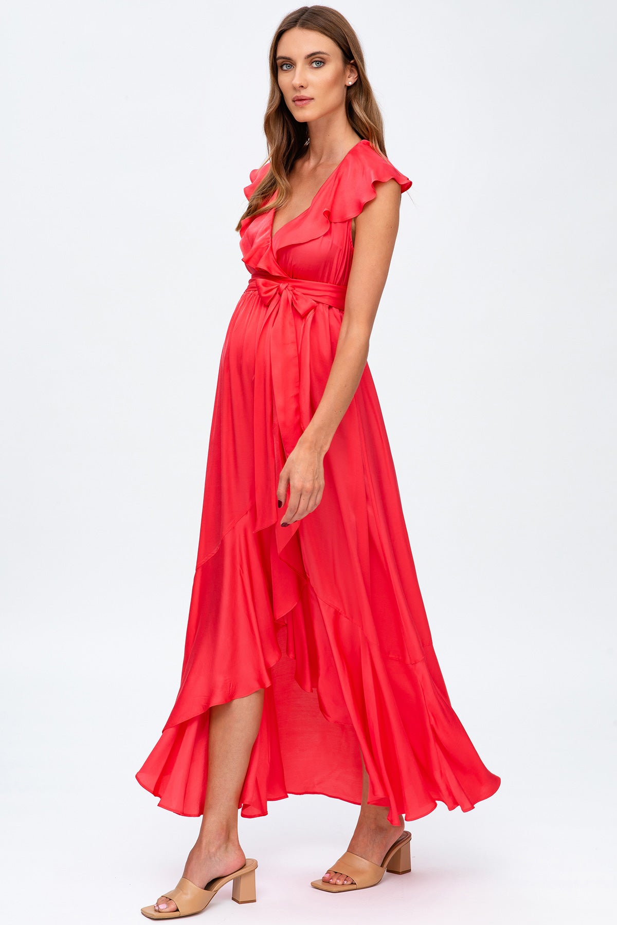 Abito premaman elegante rosa corallo con volant e cintura, tessuto leggero, donna in posa