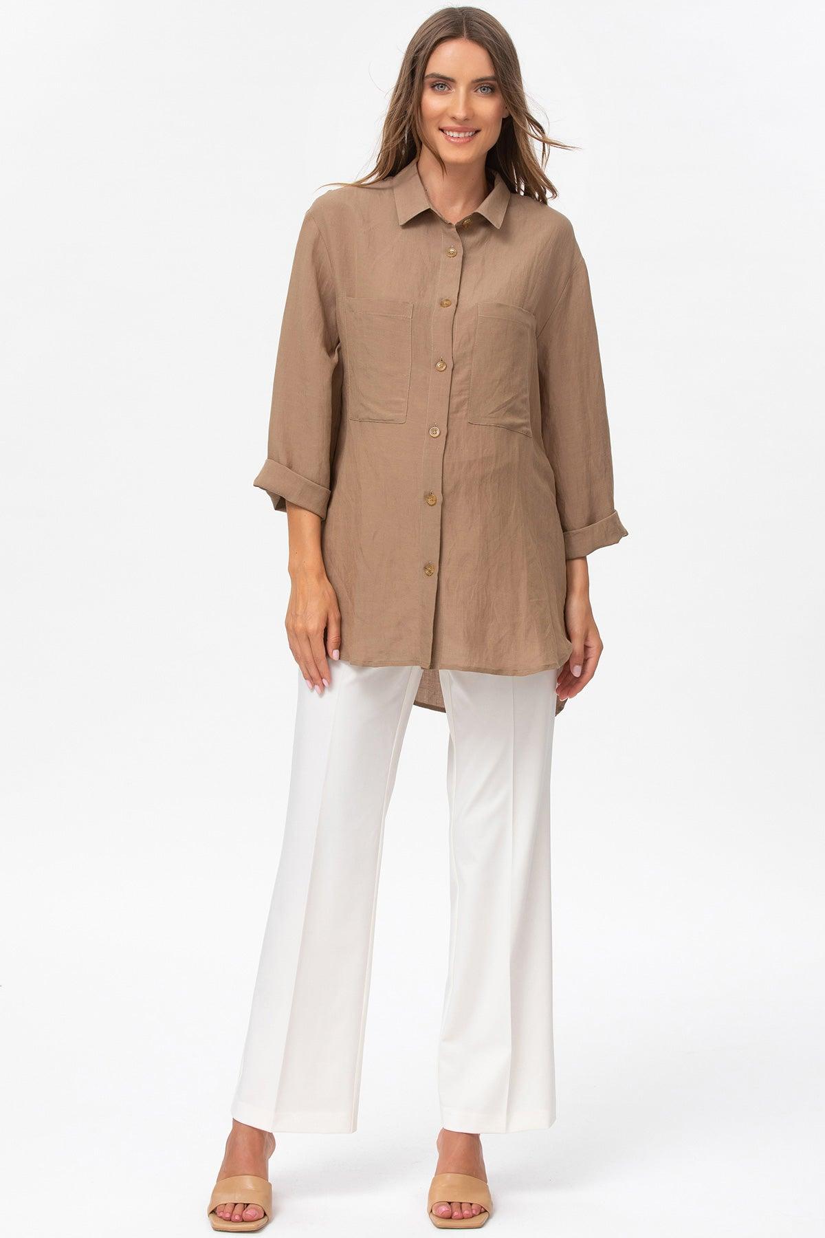 Donna con camicia premaman beige a maniche lunghe e pantaloni bianchi eleganti.