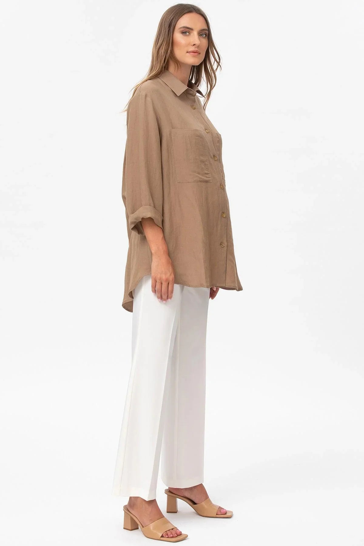 Donna indossa camicia premaman beige oversize e pantaloni bianchi eleganti