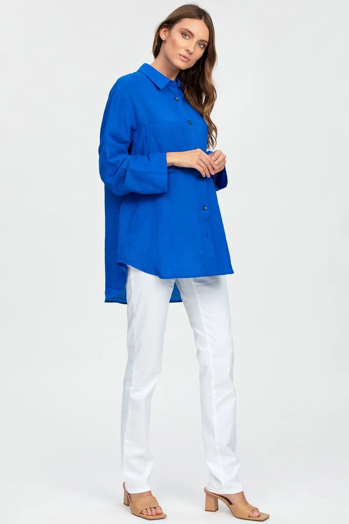 Donna con camicia premaman blu lunga e pantaloni bianchi, abbigliamento gravidanza elegante.