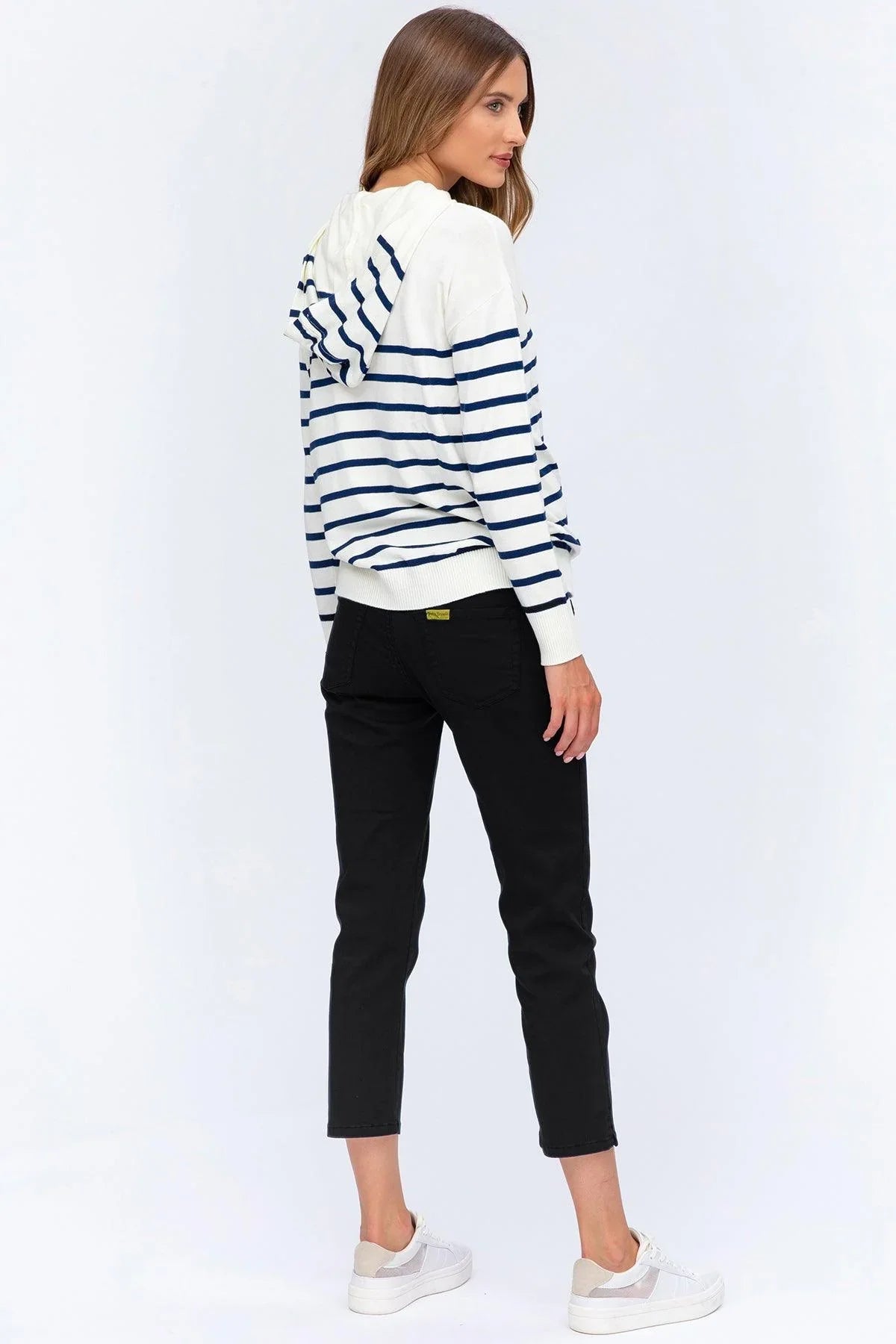 Donna con felpa premaman a righe bianche e blu, jeans neri, sneakers bianche