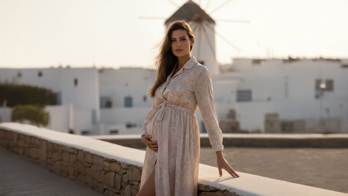Donna incinta indossa abito premaman elegante beige davanti a mulino a vento e case bianche