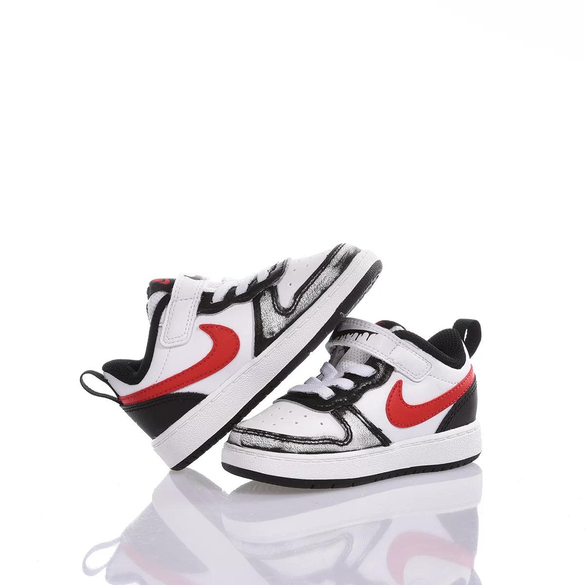 Scarpe sportive bimbo bianche con dettagli neri e logo rosso, su sfondo bianco.
