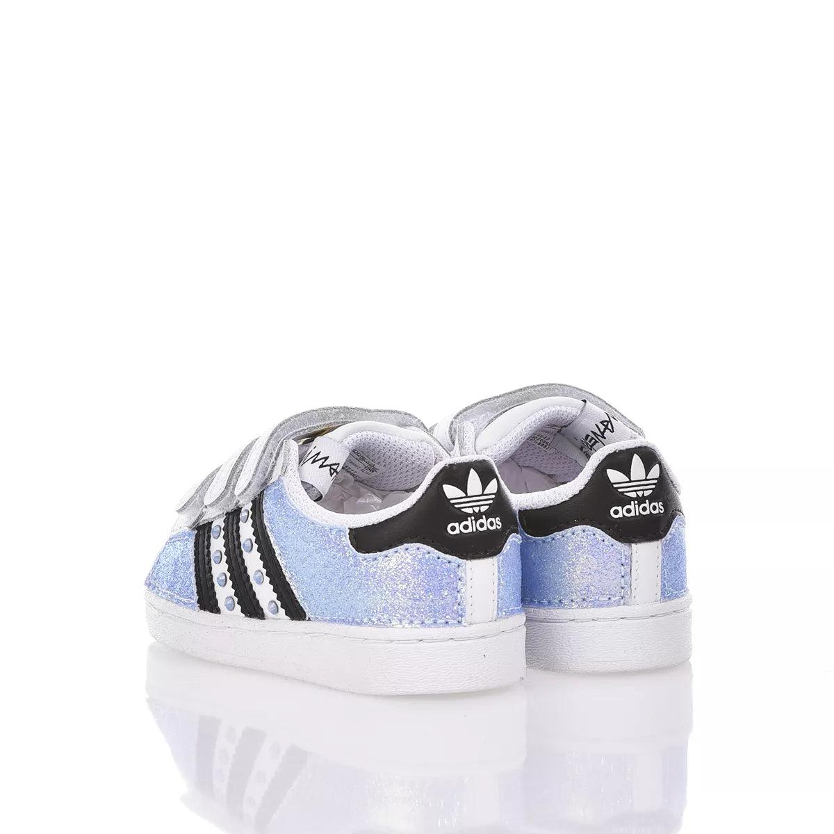 Scarpe sportive bianche glitterate per bambini con dettagli neri, adatte look premaman casual.