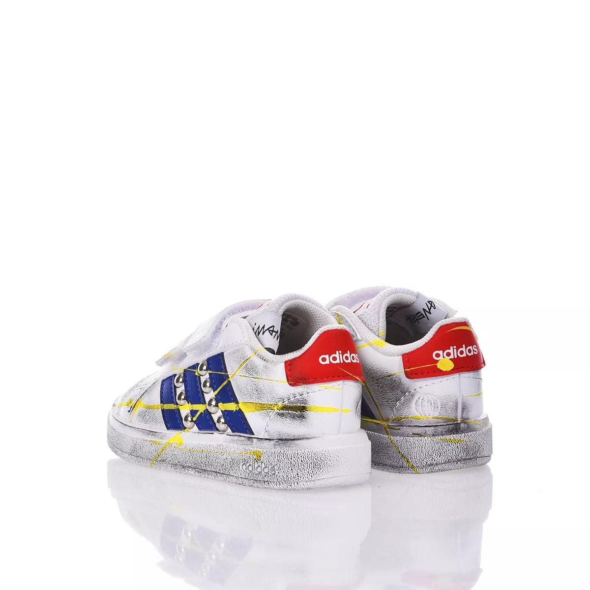 Sneakers bianche per bambini con dettagli blu, rossi e gialli, design moderno su sfondo bianco.