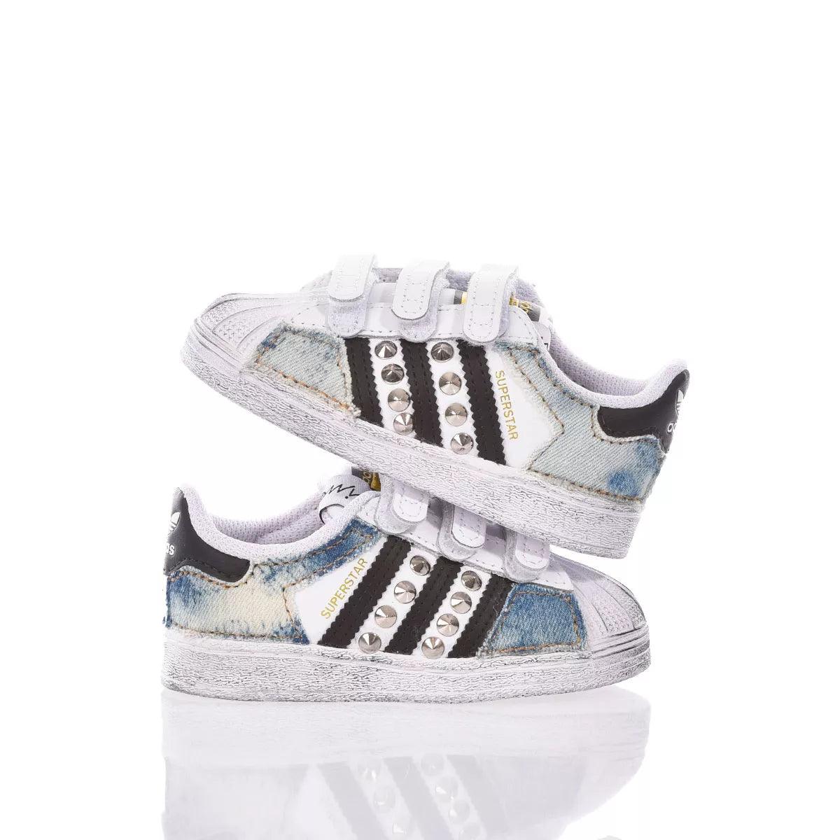 Scarpe sneakers bianche e denim con borchie, ideali per outfit premaman casual.