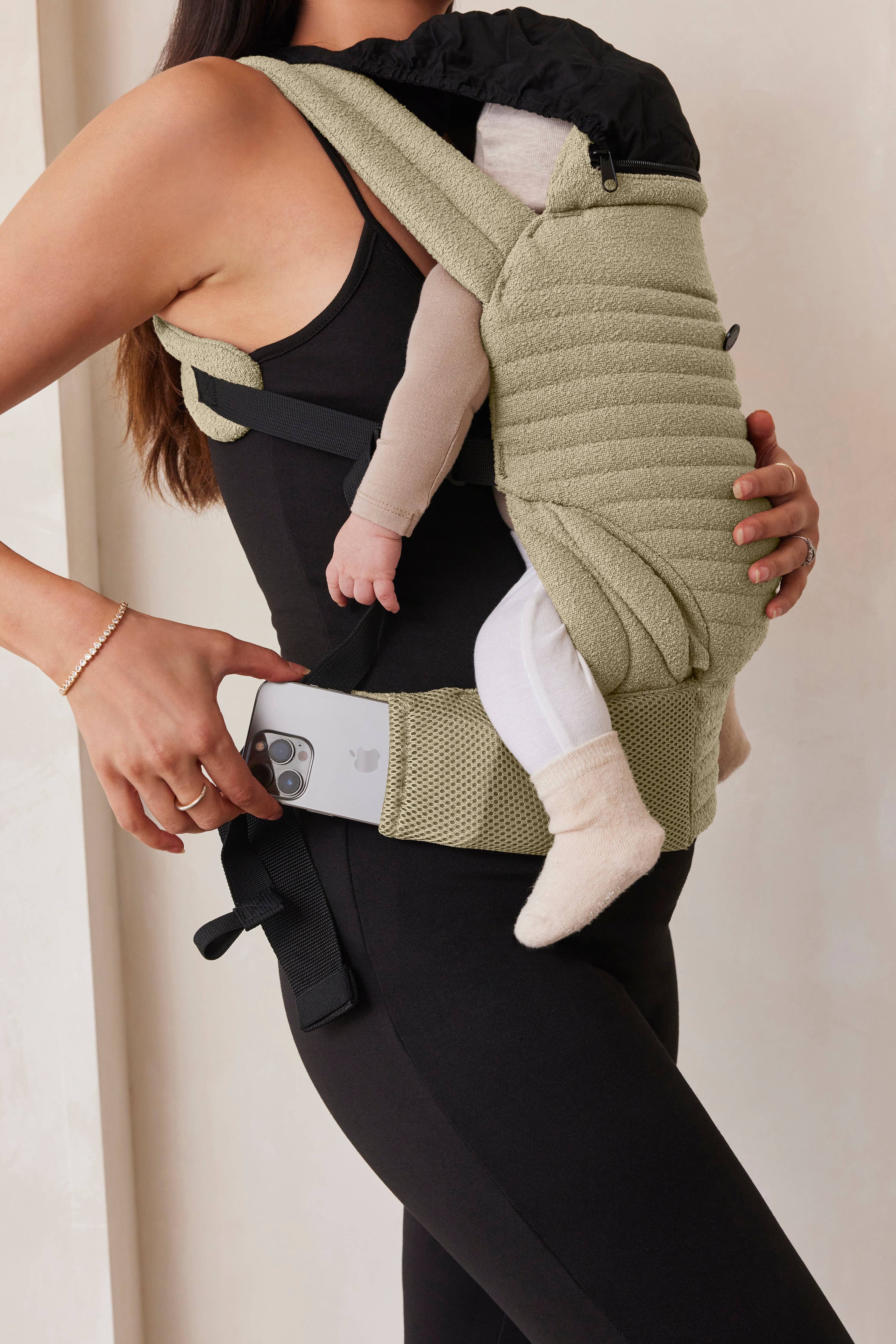 Mamma con abbigliamento premaman nero indossa marsupio per neonati beige