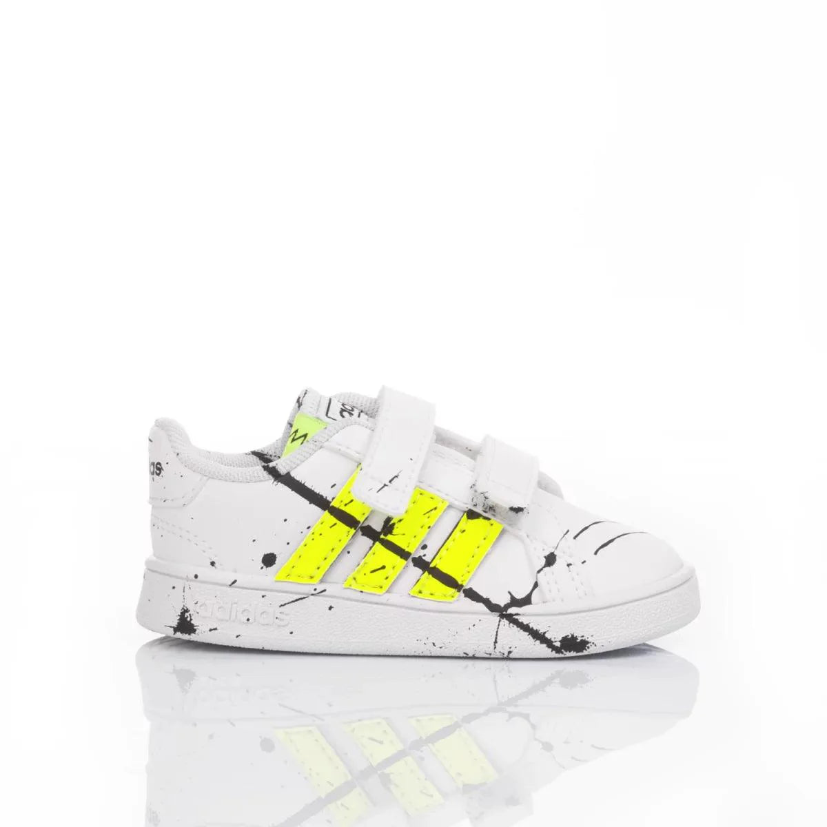 Scarpa da bambino bianca con dettagli giallo fluo, chiusura a strappo, su fondo bianco.