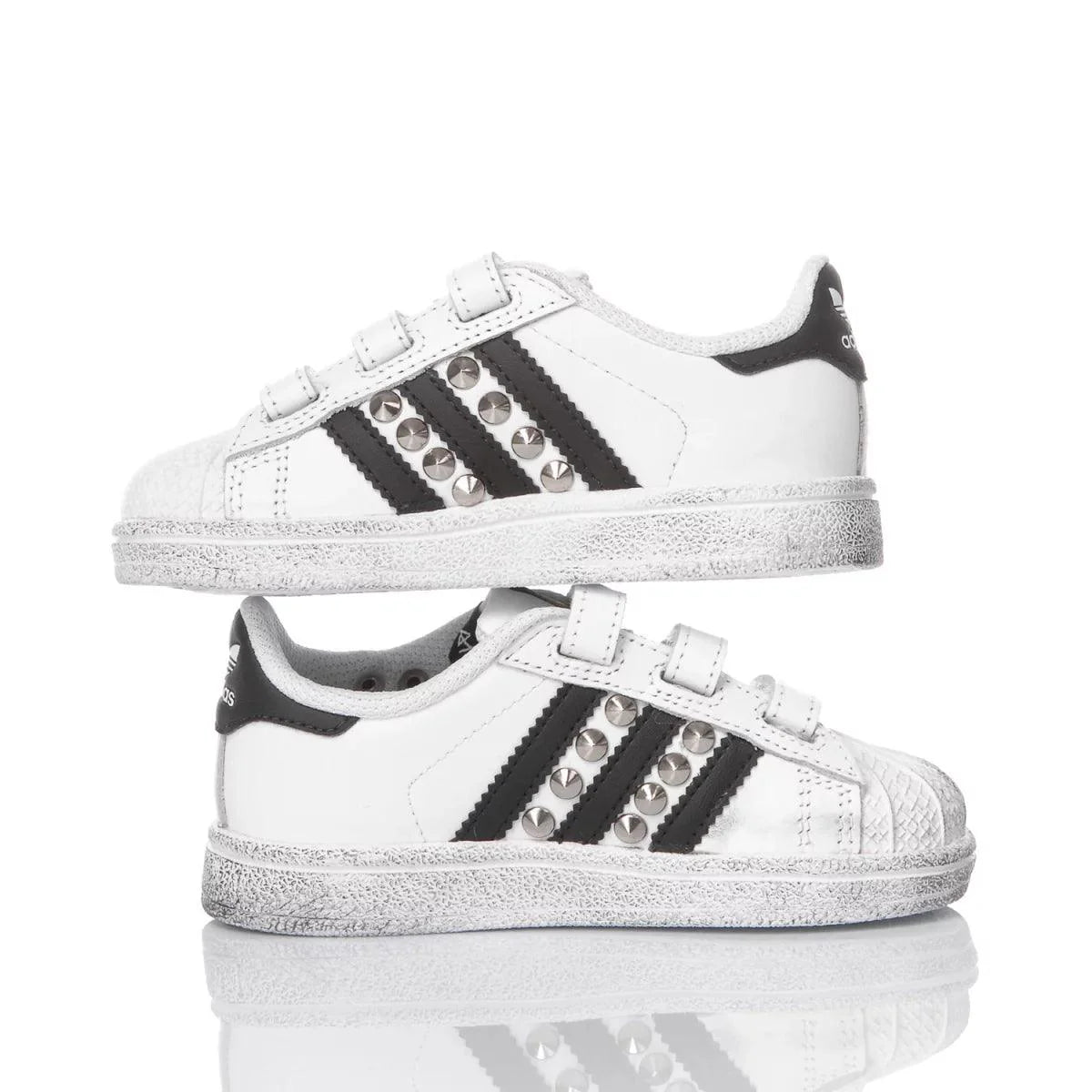 Scarpe da bambino bianche con dettagli neri e borchie, chiusura a strappo, fondo argentato.
