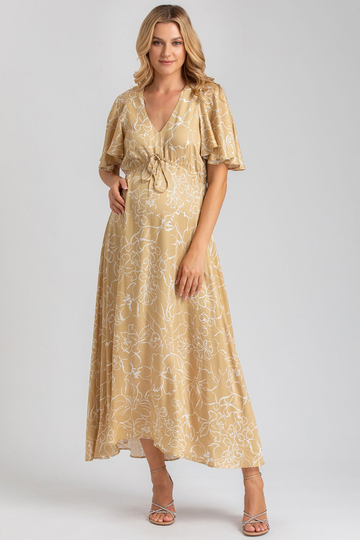 Abito premaman lungo beige con motivo floreale e maniche corte, vestibilità elegante.