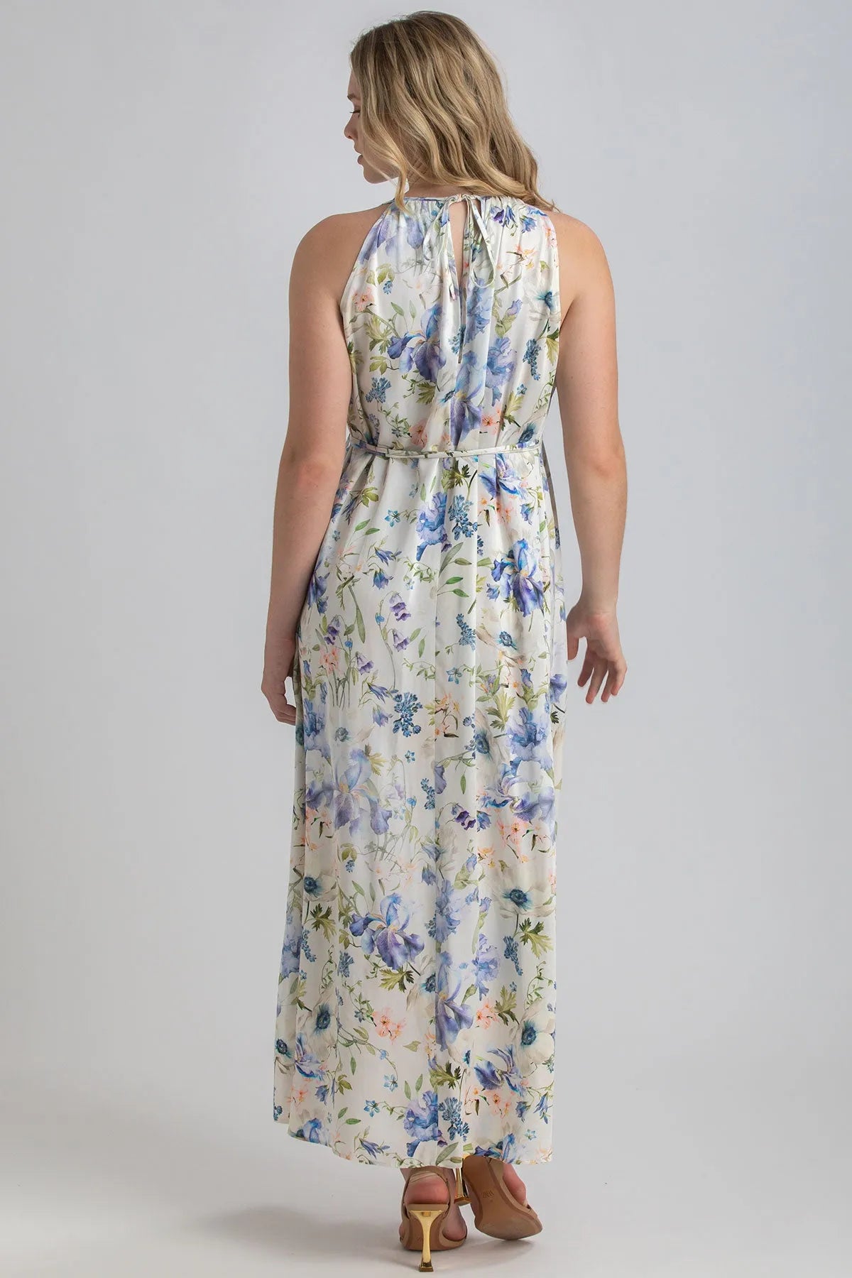 Donna di spalle con abito premaman lungo floreale, tessuto leggero, sandali nude.