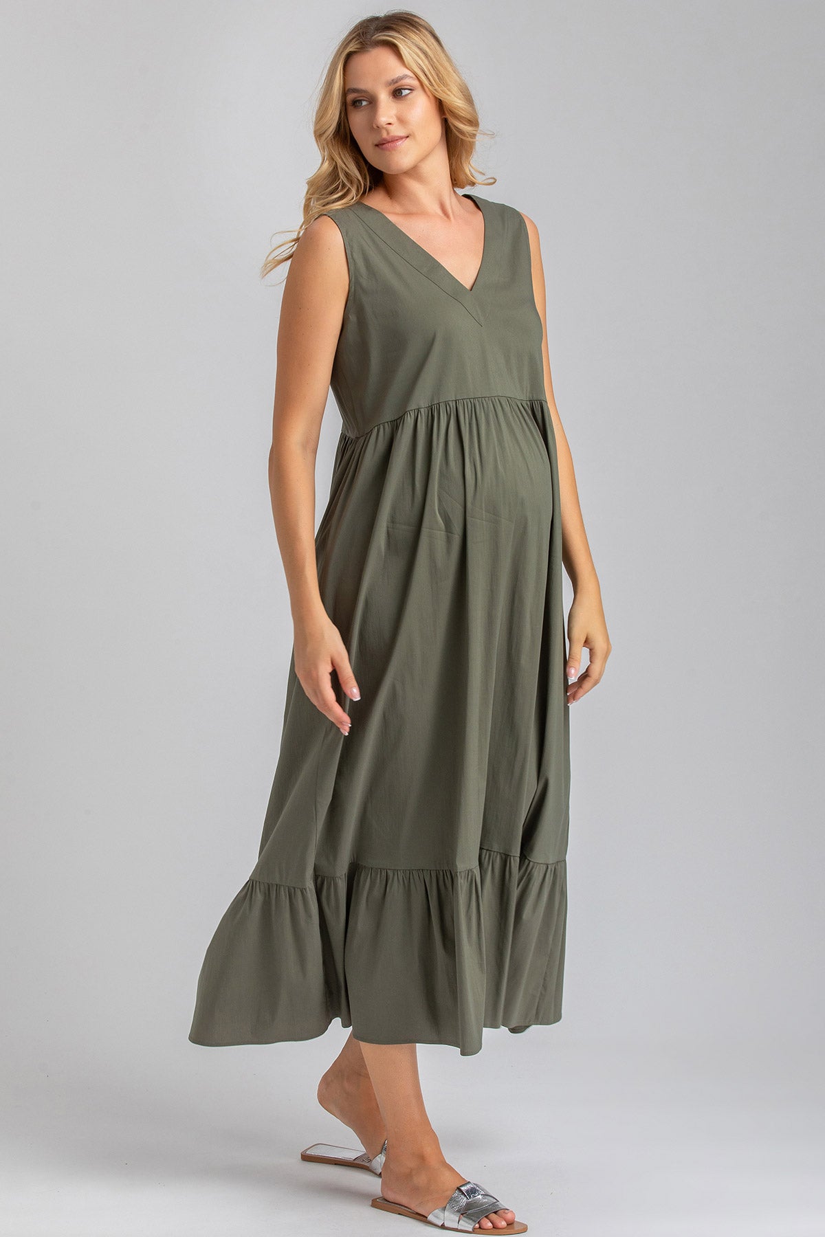 Modella indossa abito premaman verde senza maniche, con scollo a V e gonna ampia.