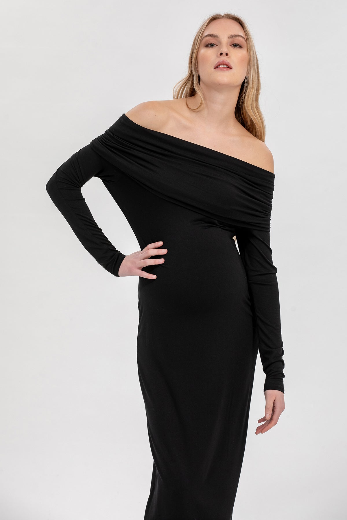 Donna incinta con abito premaman nero elegante a spalle scoperte, sfondo neutro