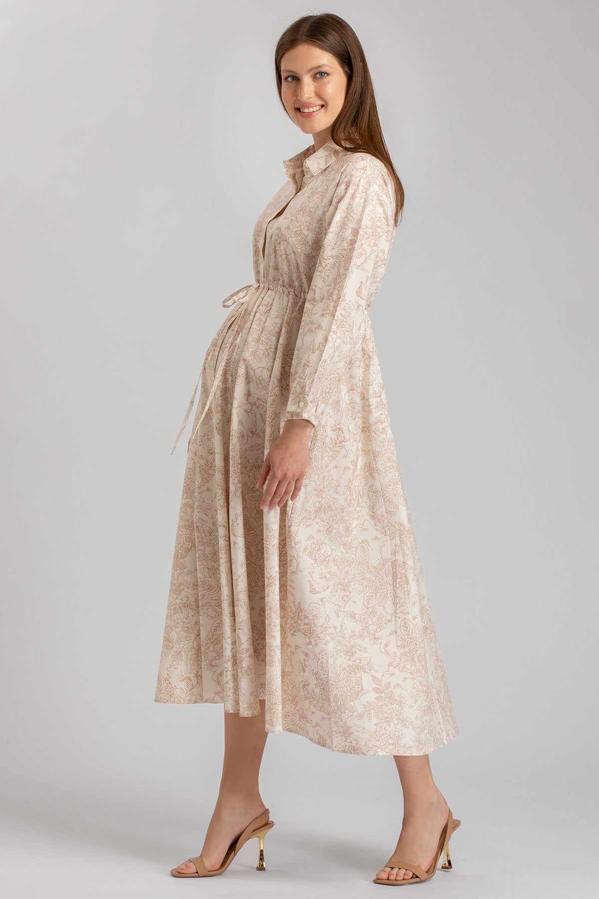 Donna incinta con abito premaman elegante a fantasia floreale beige, maniche lunghe