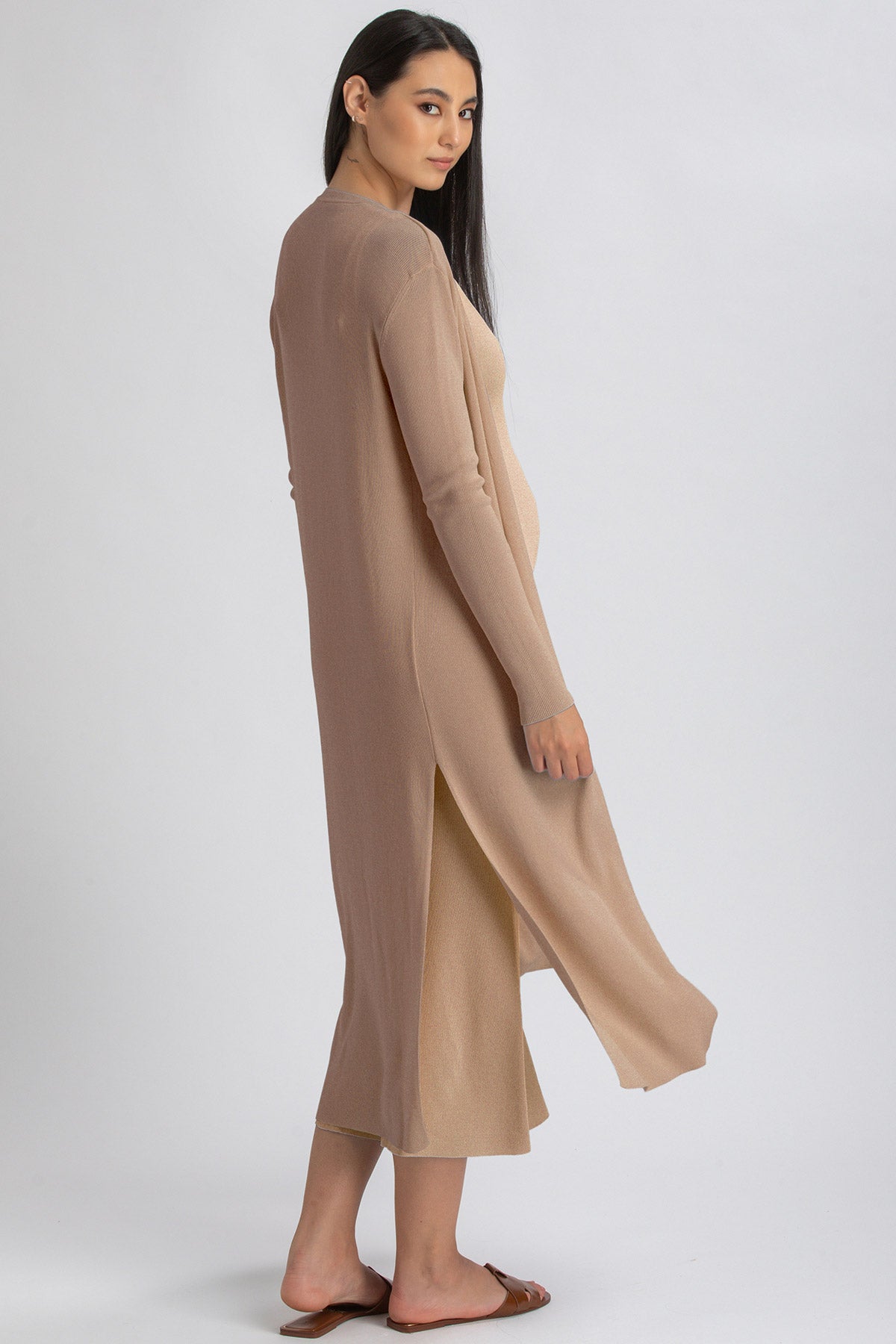 Donna incinta con abito premaman lungo beige a maniche lunghe, tessuto leggero.