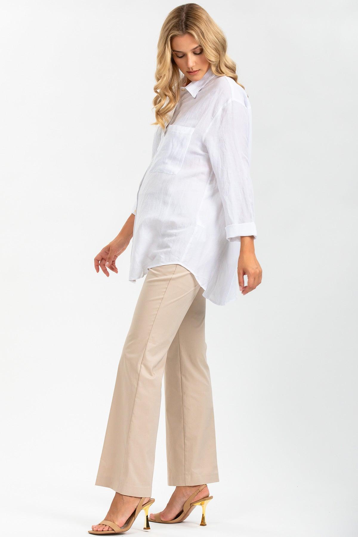 Modella premaman indossa camicia bianca oversize e pantaloni beige eleganti