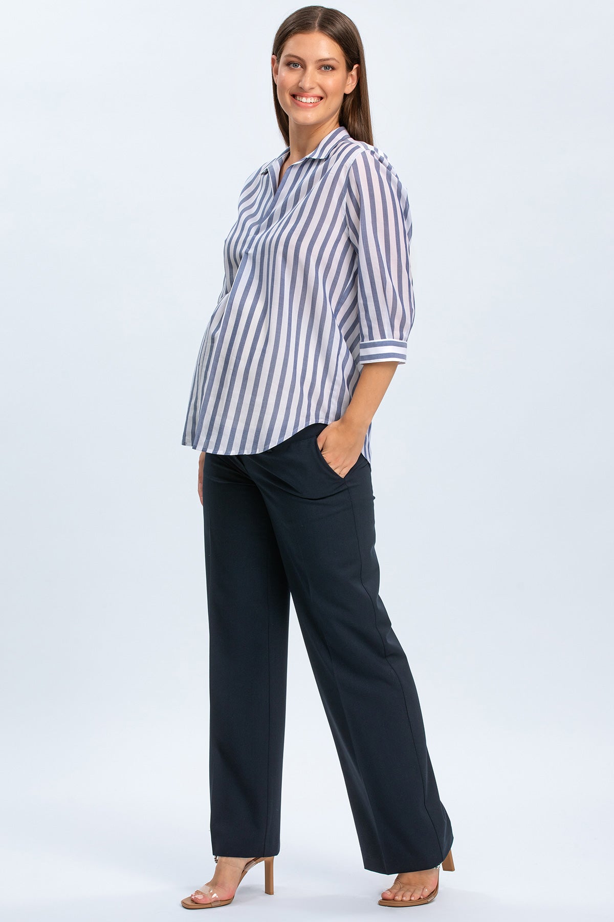 Donna incinta con camicia premaman a righe blu e pantaloni eleganti premaman.