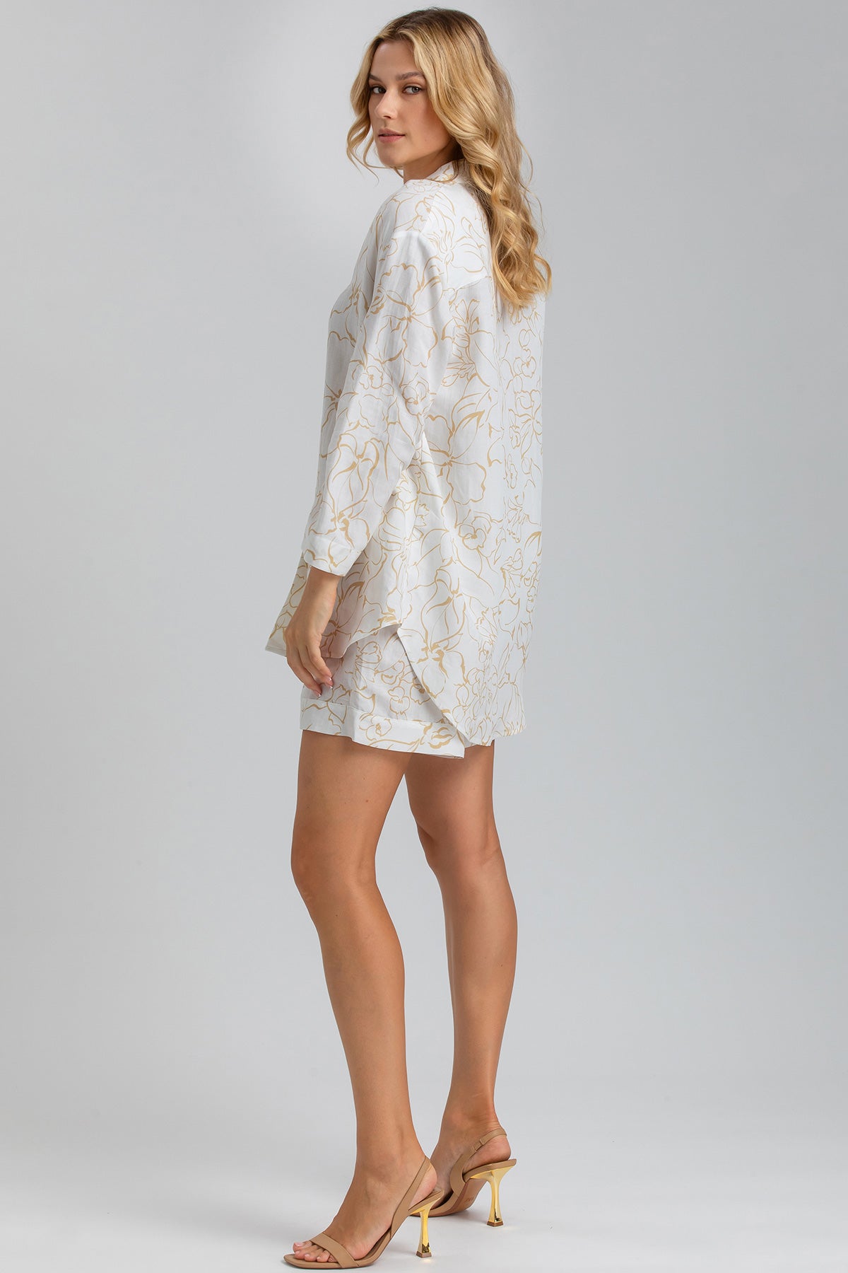 Modella indossa completo premaman elegante bianco con motivo floreale oro e tacchi beige