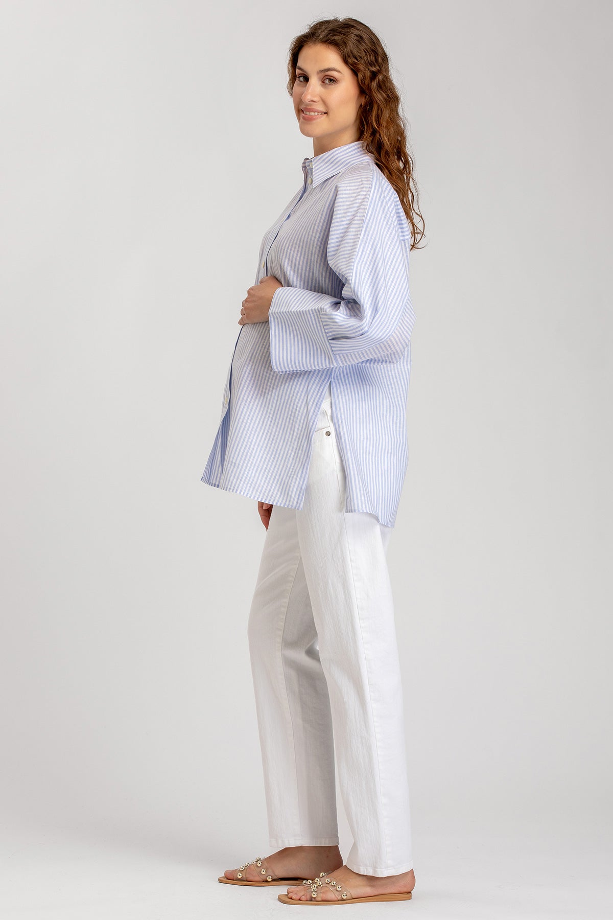 Modella premaman indossa camicia azzurra a righe e pantaloni bianchi, abbigliamento premaman elegante