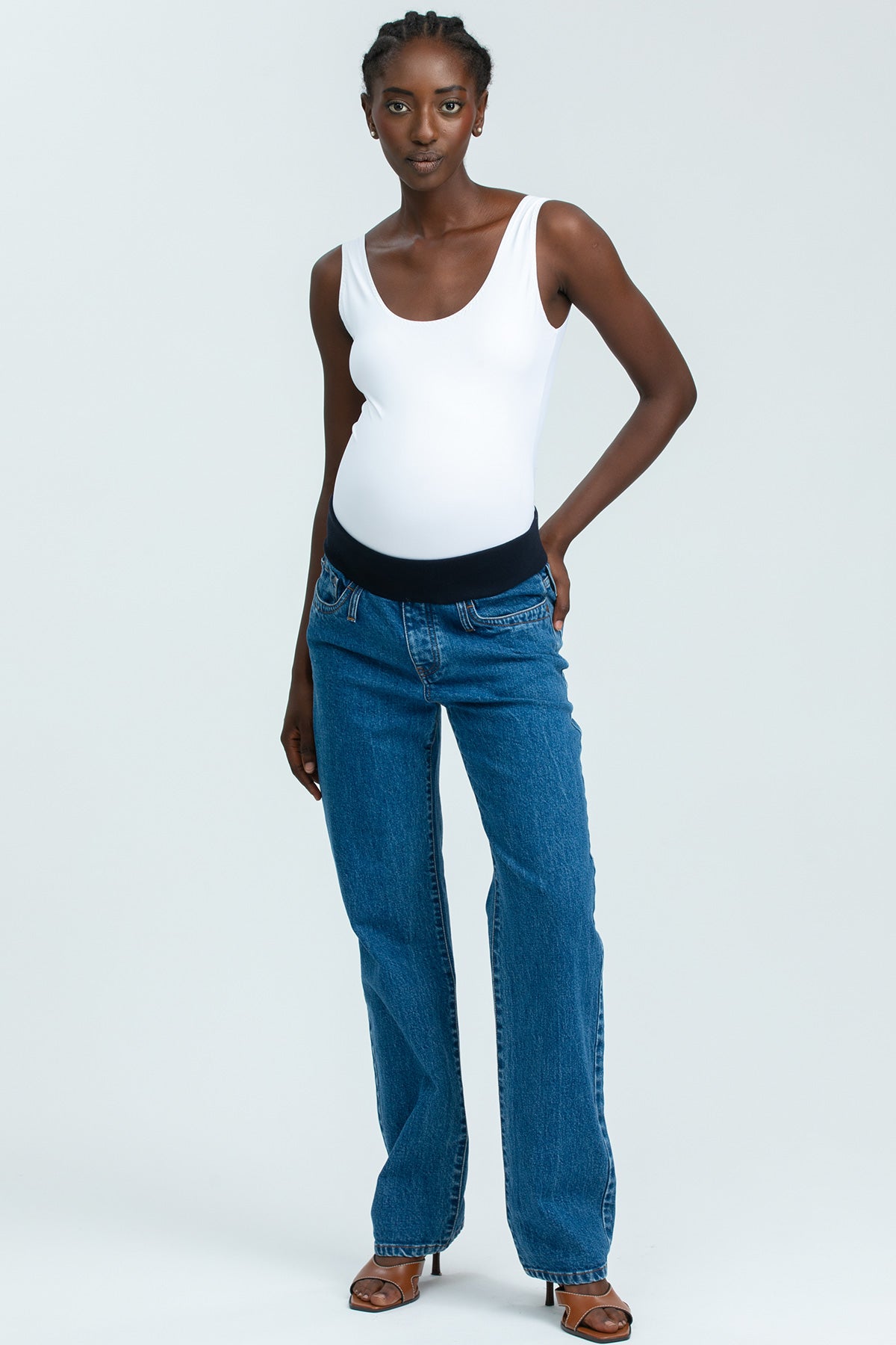 Model wearing high-waisted straight-leg maternity jeans with a comfortable stretchy belly band, styled for an elegant maternity look.