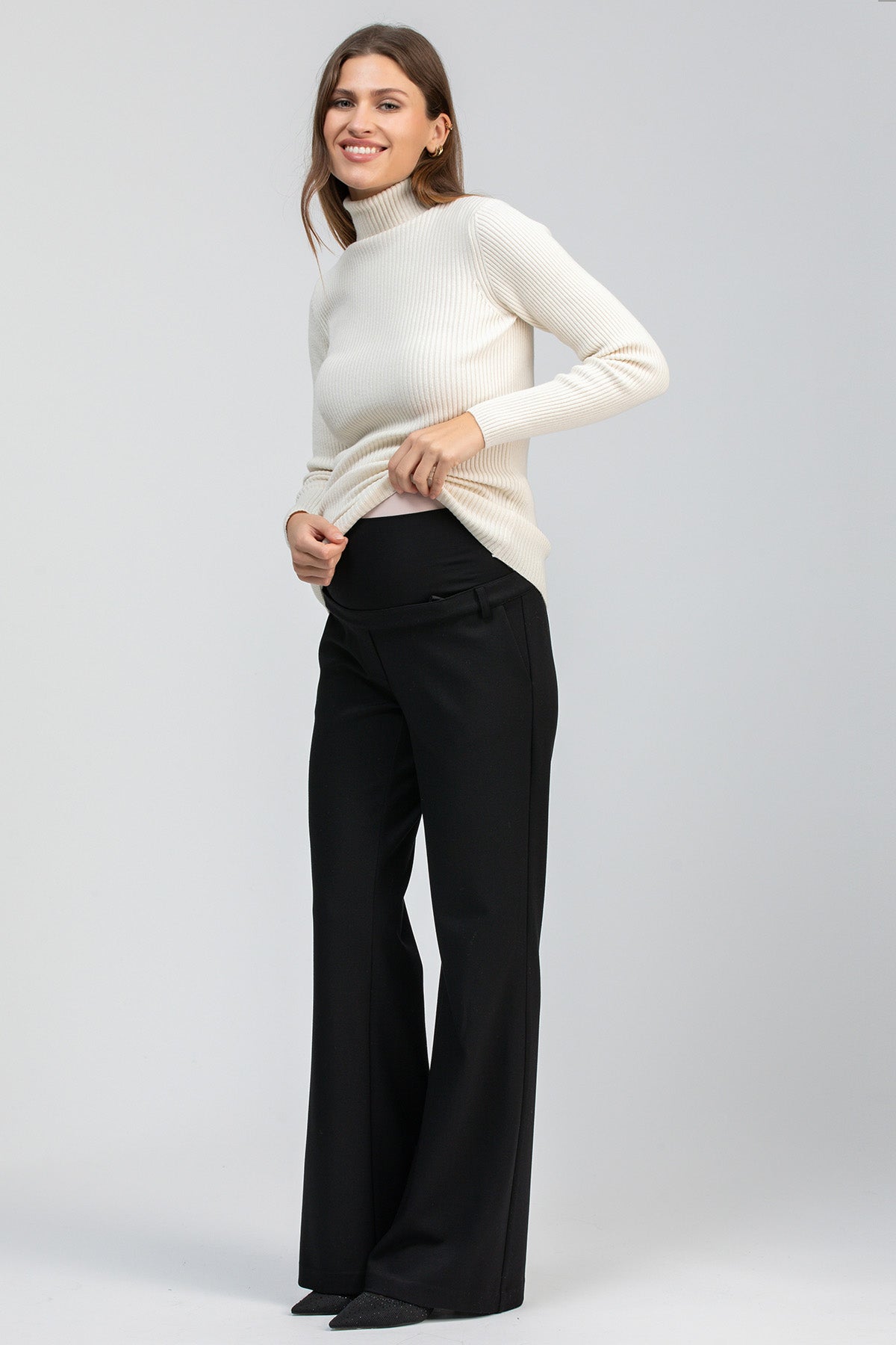 Donna incinta con maglia a collo alto bianca e pantaloni premaman neri eleganti