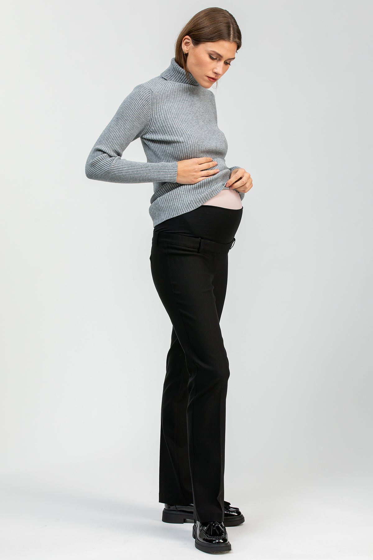 Donna incinta indossa pantaloni premaman neri eleganti e maglione grigio a collo alto