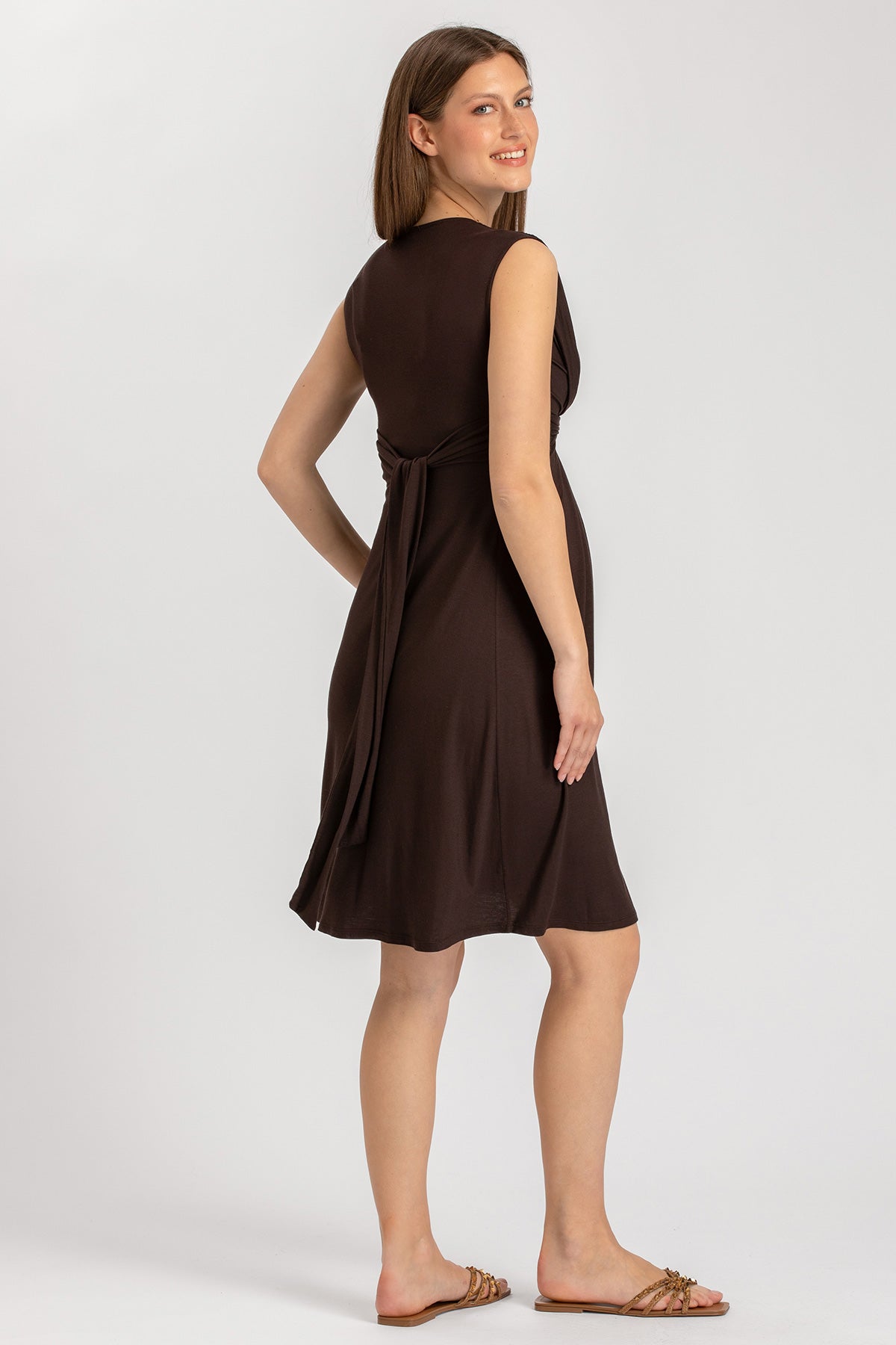 Vestito premaman marrone senza maniche, modello corto, con cintura, indossato da donna incinta.